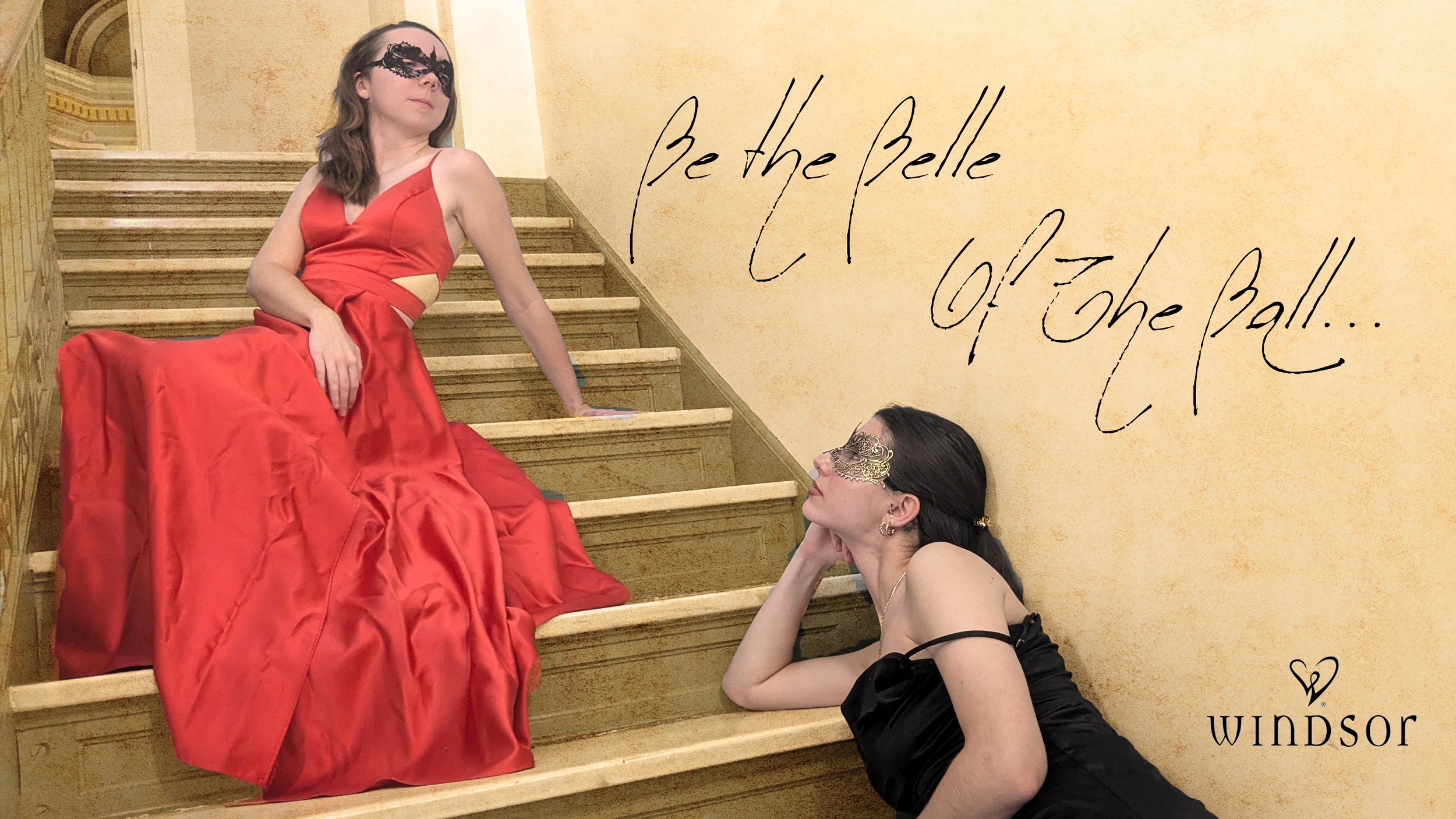 Two women wearing elegant dresses and masquerade masks pose on a staircase in a fancy setting. One woman in a red gown sits on the stairs, while the other woman in a black dress lies on a lower step, looking up at her. The background has a textured, warm-toned wall with handwritten-style text that reads 'Be the Belle of the Ball...' and a Windsor logo with a heart icon.