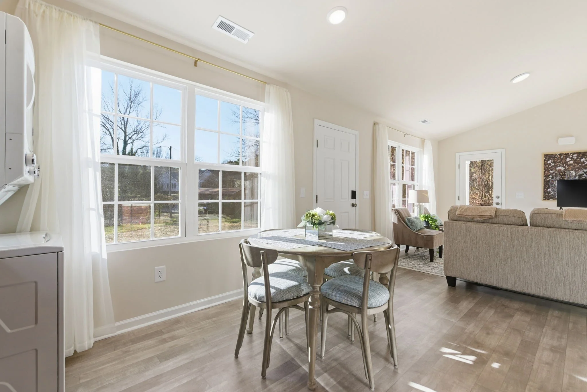 Bright, open-concept floor plan showing the seamless flow between the dining and living areas. Large windows offer tranquil views of the Durham greenery.