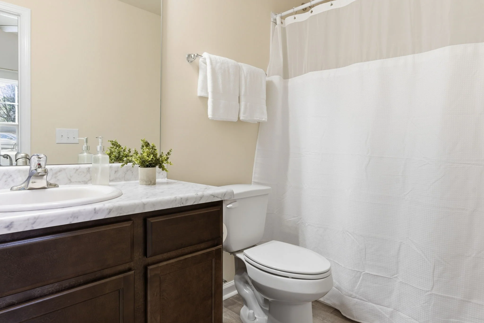 Modern, sparkling clean bathroom featuring a faux marble topped vanity and a large shower. We provide plush towels and essentials for a hotel-quality experience in our dog-friendly rental.