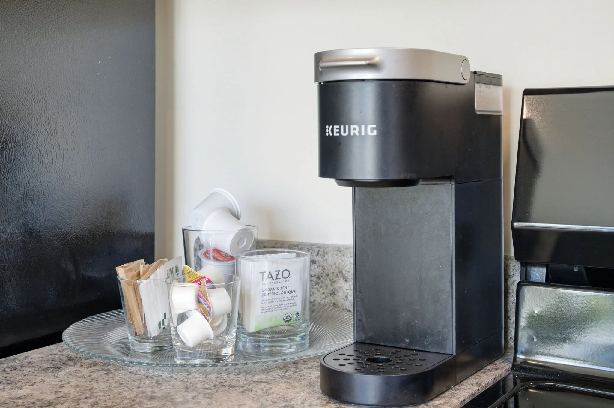Complimentary coffee bar featuring a Keurig machine, Tazo tea, and a variety of pods. A thoughtful amenity for early shifts at Duke Medical Center or morning remote work.