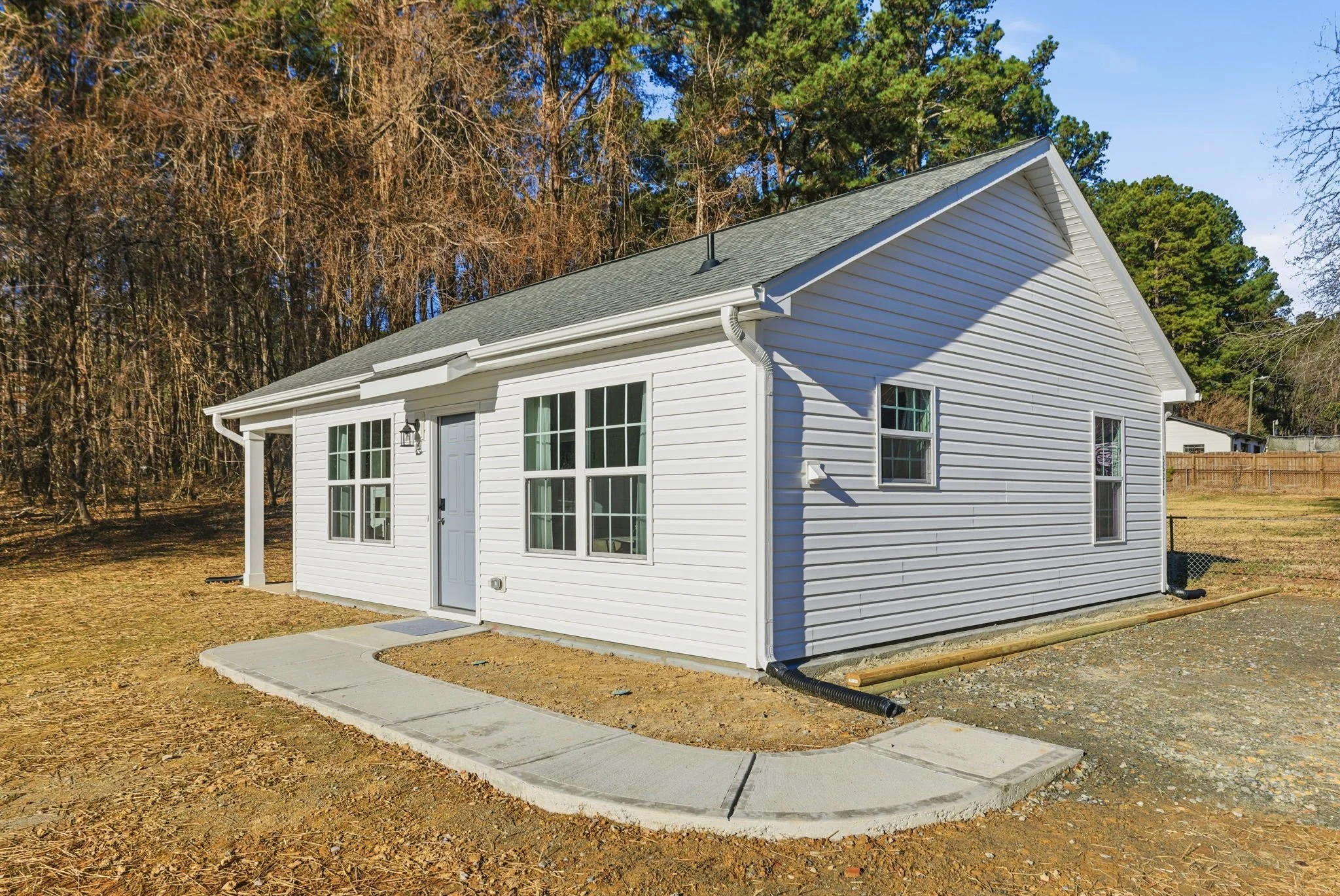 This bright and airy guest house features a private concrete walkway and a secure, keyless entry for seamless check-ins. The modern white siding and clean architectural lines reflect the brand-new construction of this premium guest suite.
