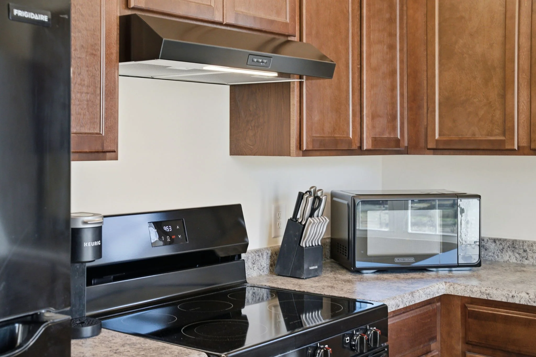 Gourmet kitchen setup featuring a Frigidaire glass-top range, Frigidaire refridgerator, Black & Decker microwave, and a Keurig for your coffee.  Our fully stocked kitchen ensures you have everything needed to cook home-style meals during your stay.