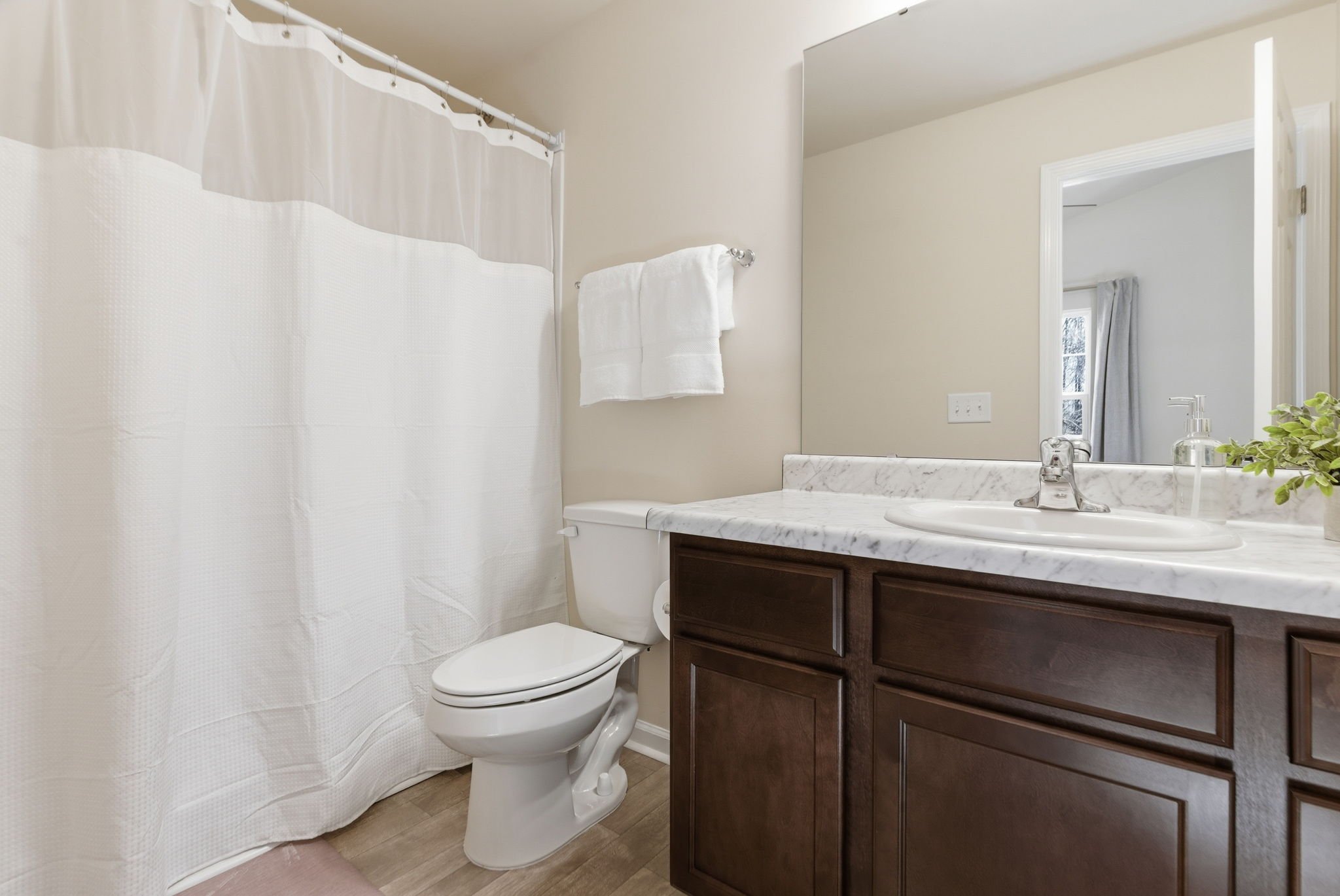 Refresh in this bright, clean bathroom featuring a faux marble-topped vanity and ample storage. Whether you visit for a short or extended stay, we provide essentials including toiletries and plush white towels to make your stay effortless.