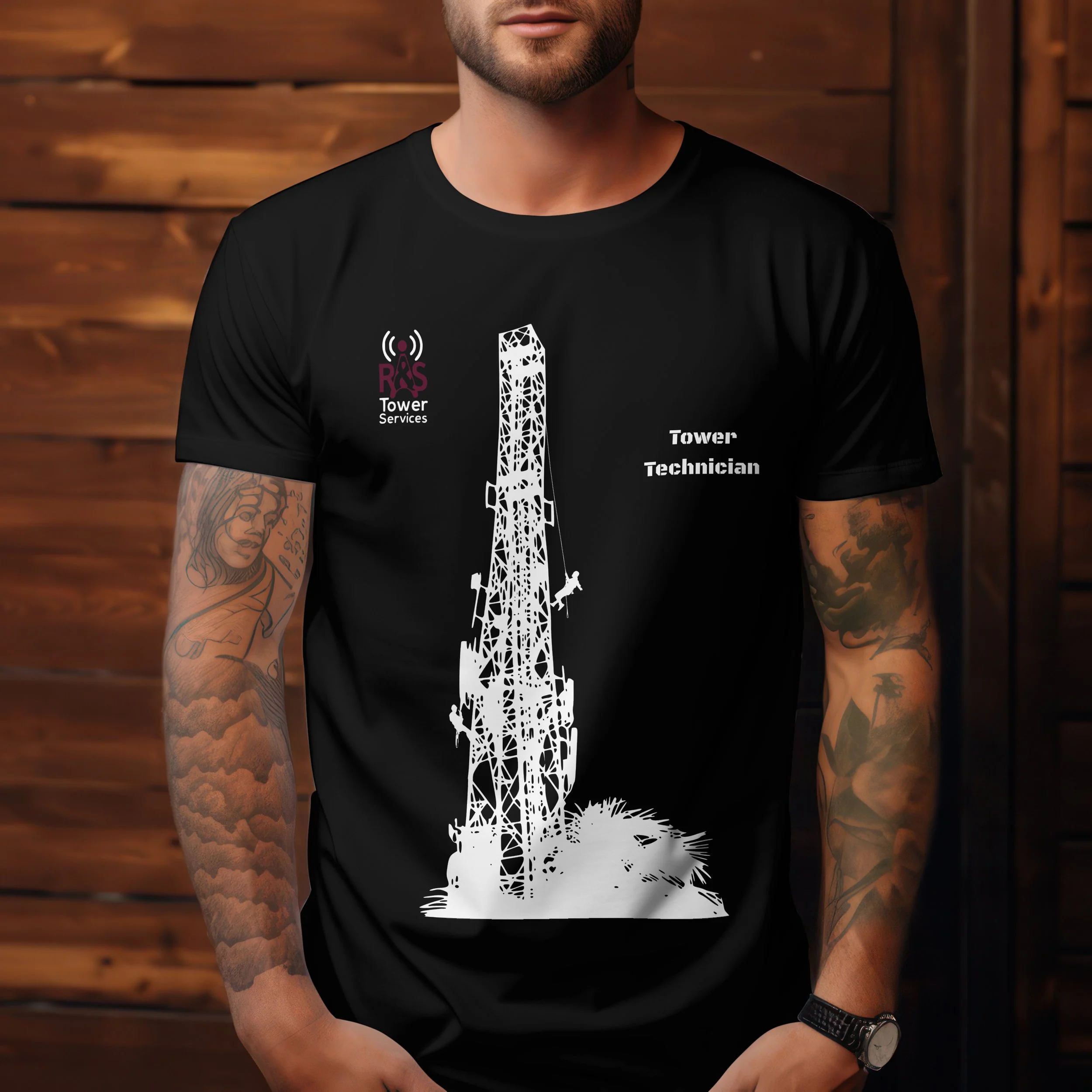 Black t-shirt with a white illustration of a tower and the words 'Tower Technician' printed on it, worn by a man with tattoos on his arms, standing against a wooden background.