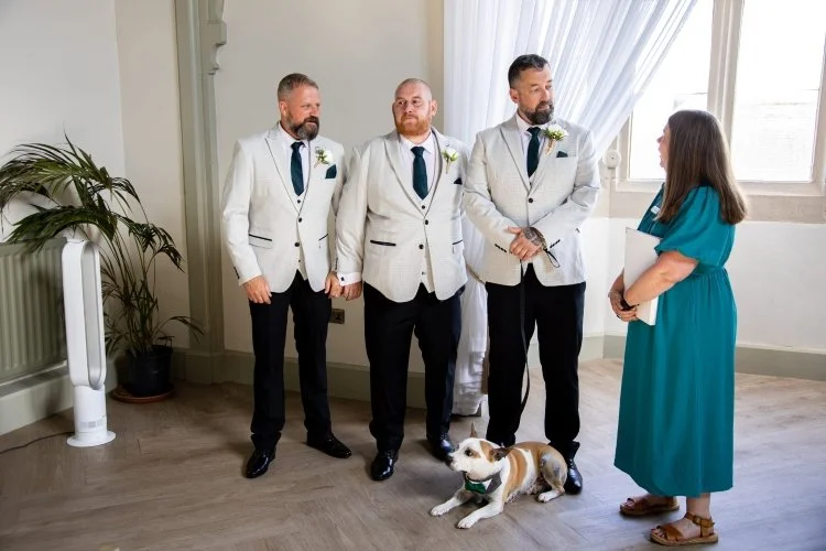 Before the wedding ceremony begins, Kate is talking with the groom who is accompanied by two best men and the family dog.
