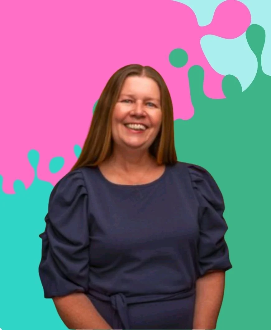 In this image Kate is wearing a dark blue dress and is smiling in front of a colourful paint splash effect background. There are pink, mint, and cyan blue colours in the background.