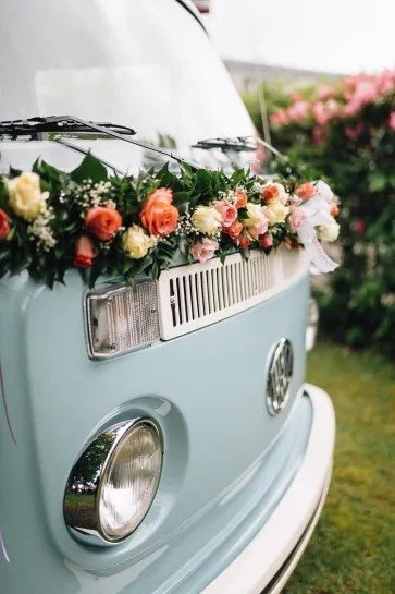 Link to the wedding and vow renewals page. The image shows the front of a vintage camper van decorated in flowers.