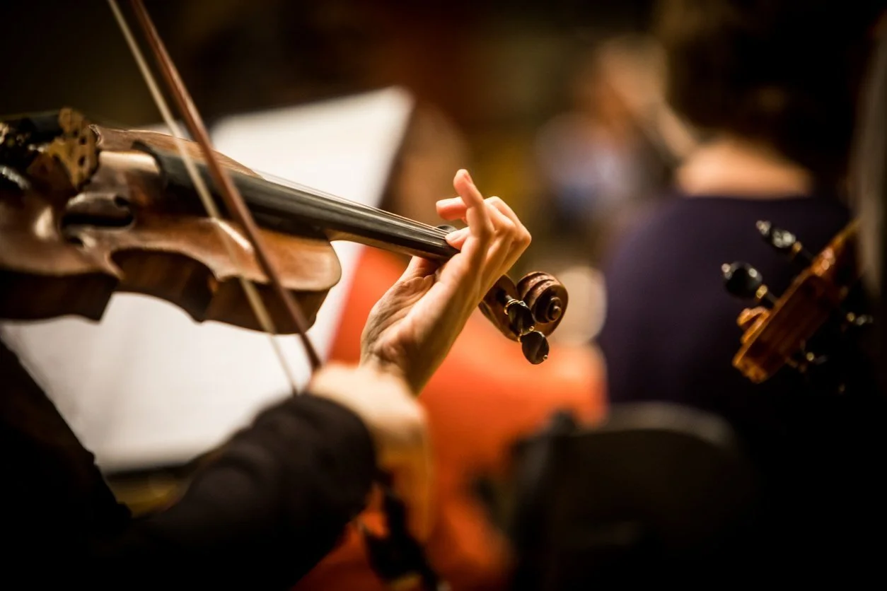 Close-up of a person playing a violin with focus on the hand and fingerboard.
