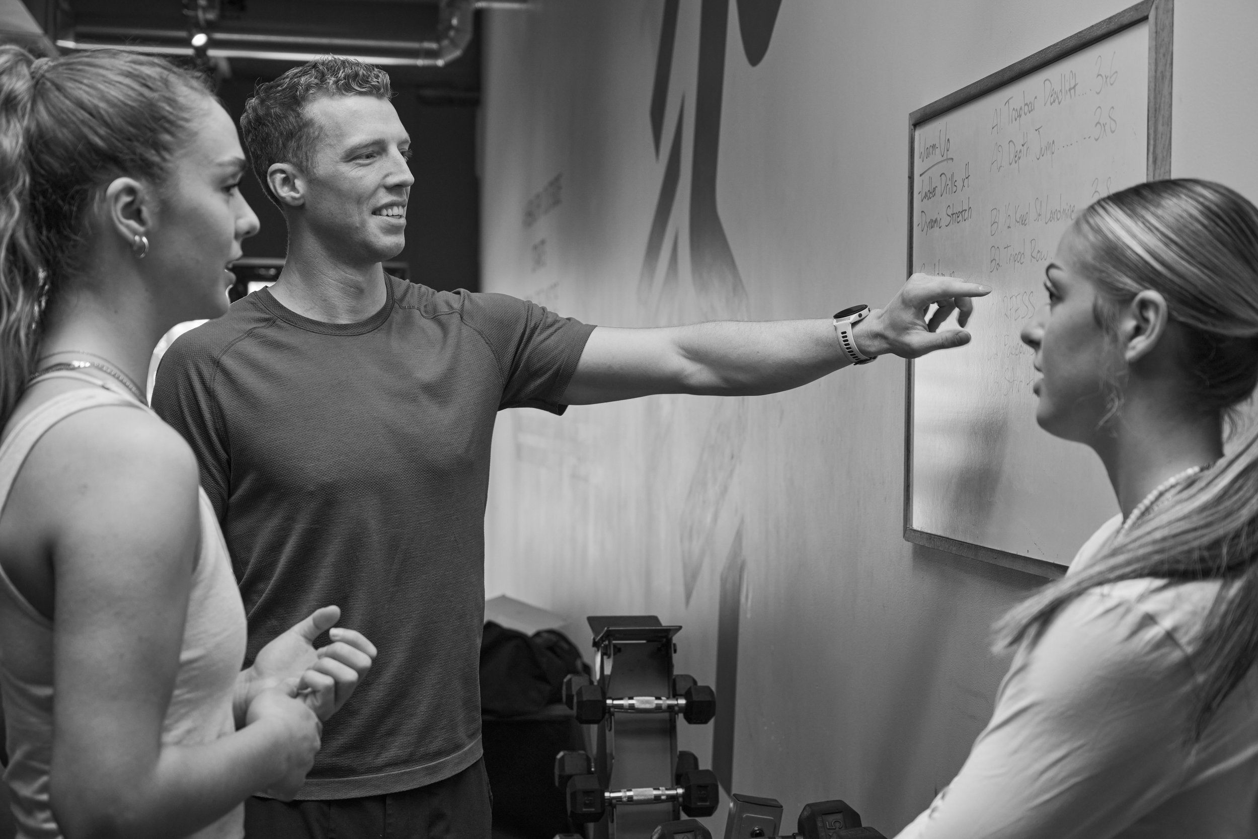 A volleyball coach reviewing a workout with two athletes.