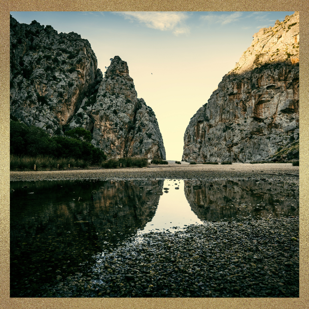A canyon passage between two rocky cliffs with still water reflecting the divide, symbolizing the gap between being a respected physician and being trusted for a larger leadership role.