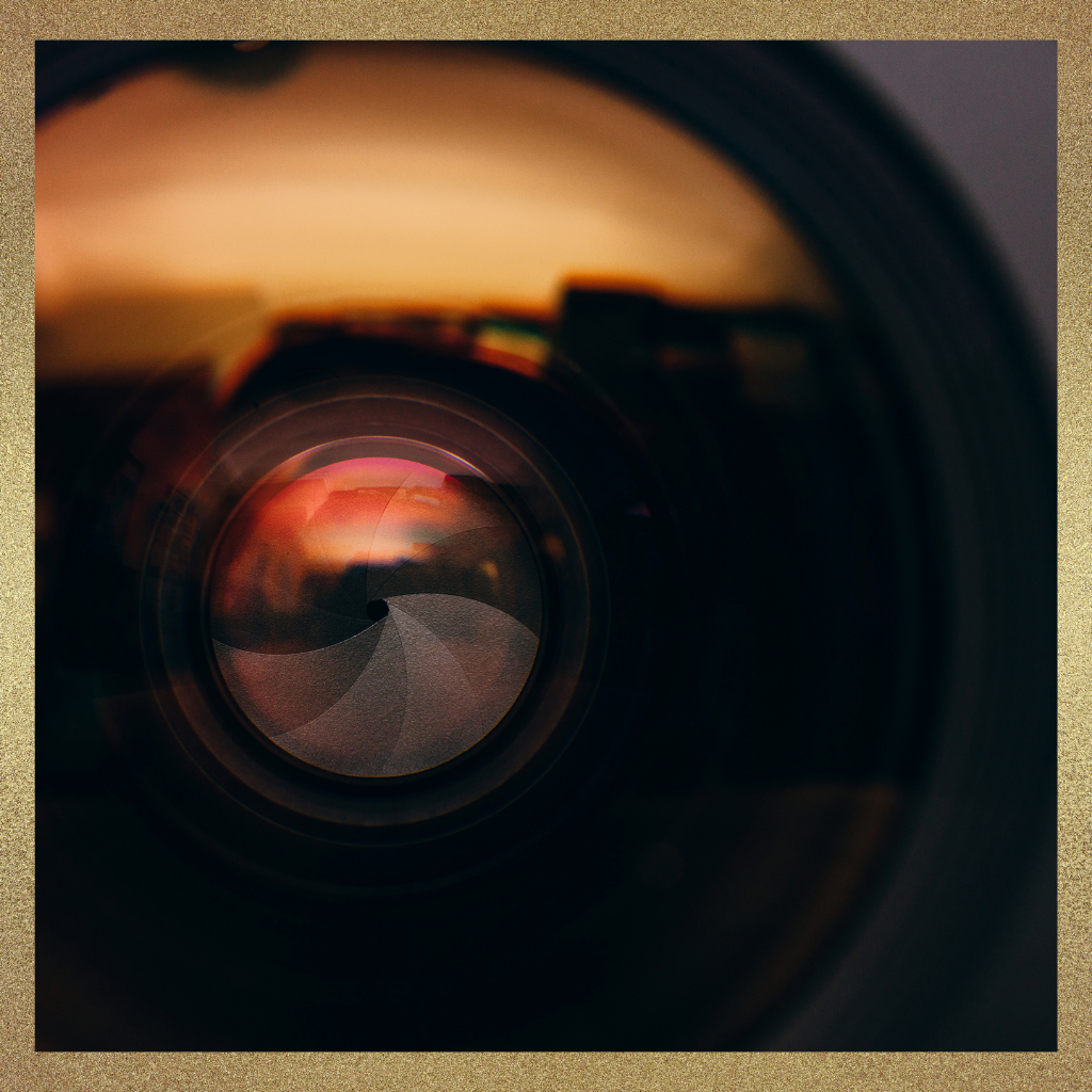 Close-up of a camera lens with warm reflected light, symbolizing how physician leadership judgment depends on the scope and lens through which a decision is viewed.