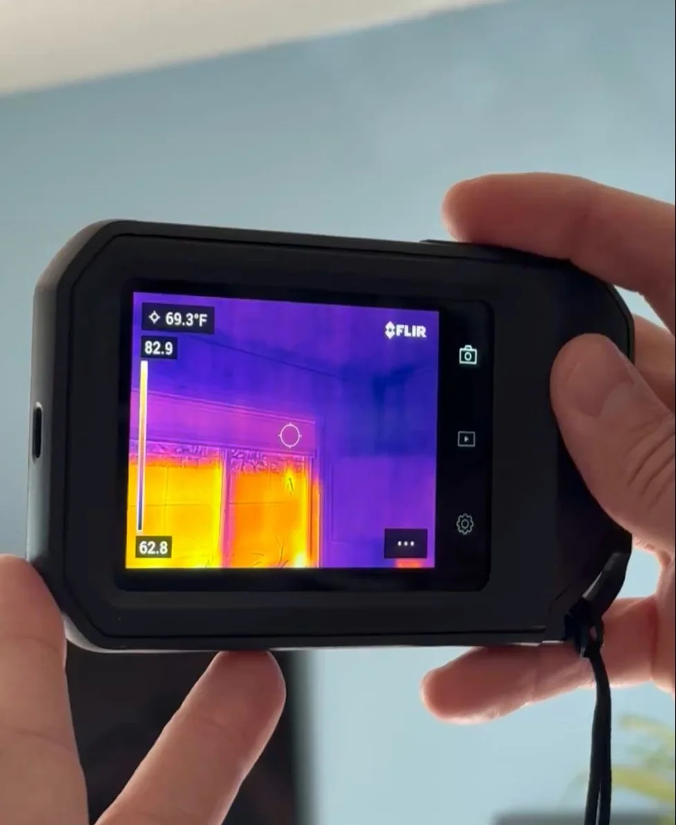 Home inspector using a FLIR thermal camera to check a wall for moisture and missing insulation in a Minnesota home.