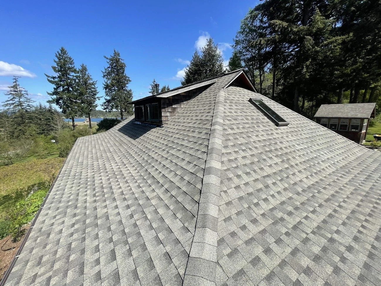New gray shingle roof on a wooded island home with water view