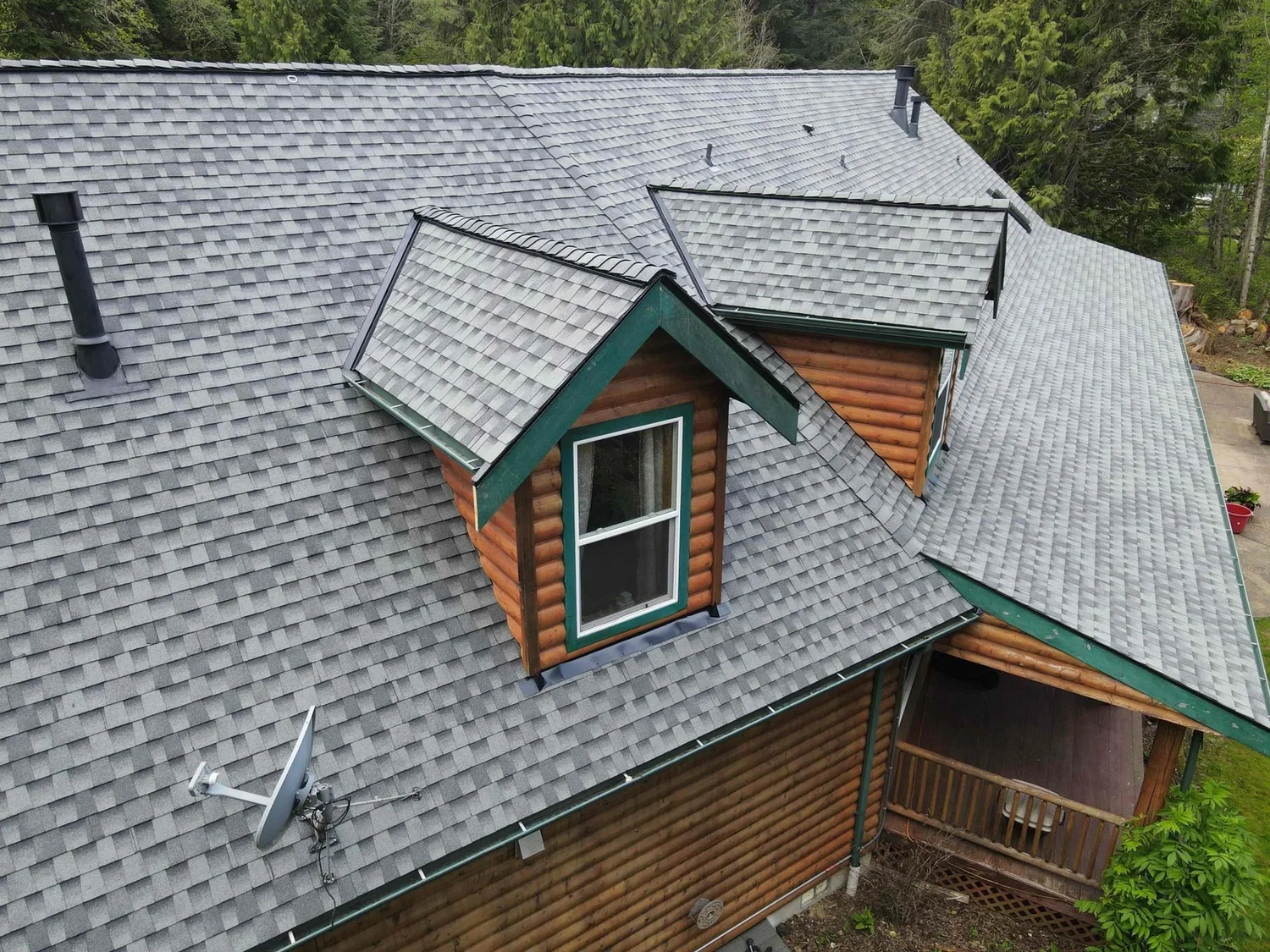 Gray architectural shingle roof Topside installed on a log home with green trim