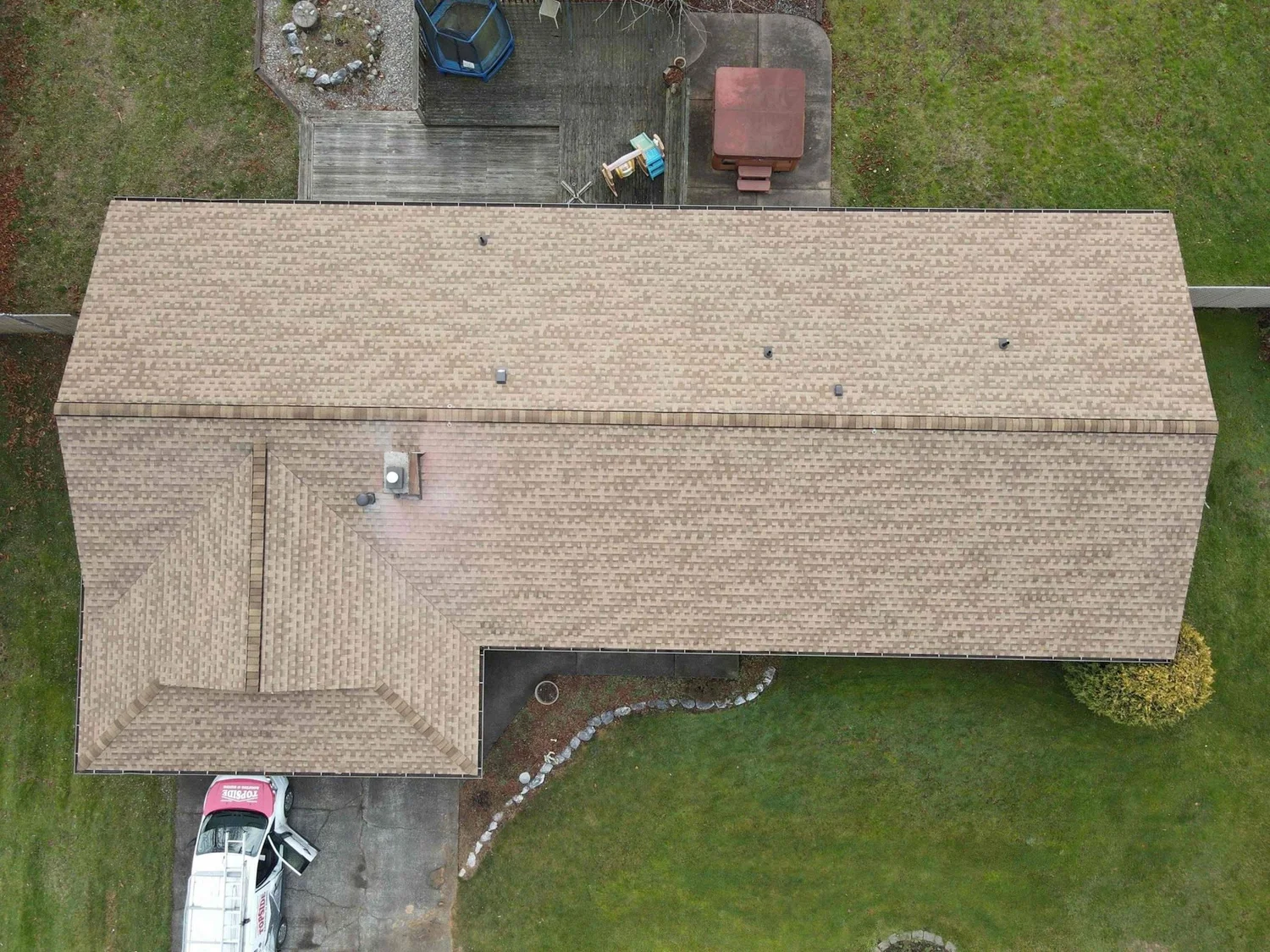 Drone view of a tan shingle roof with Topside truck in the driveway