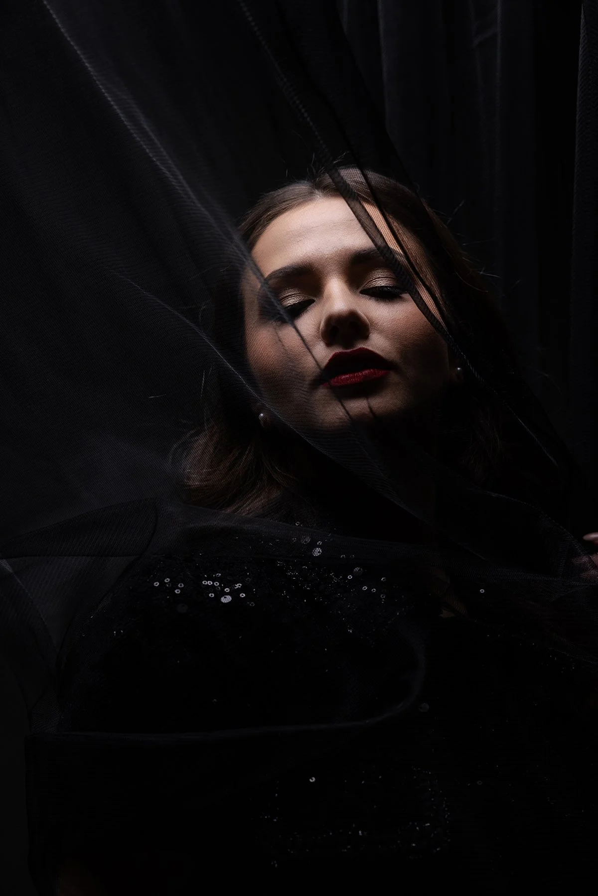 A closeup photo of a model posing with black tulle for an editorial studio photoshoot