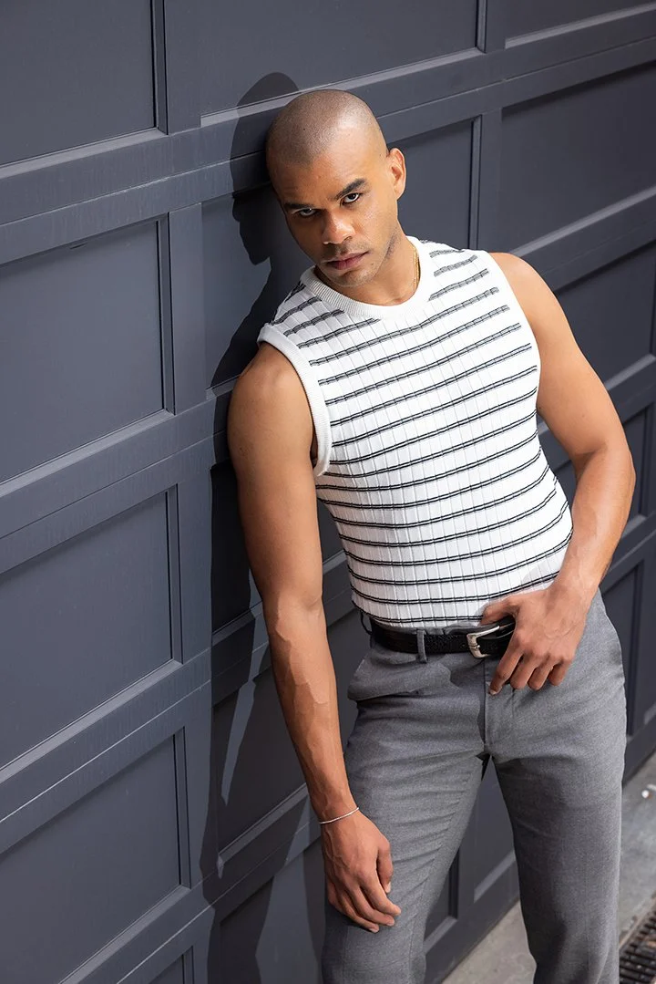 A man leaning on a gray garage door, posing for a lifestyle photoshoot