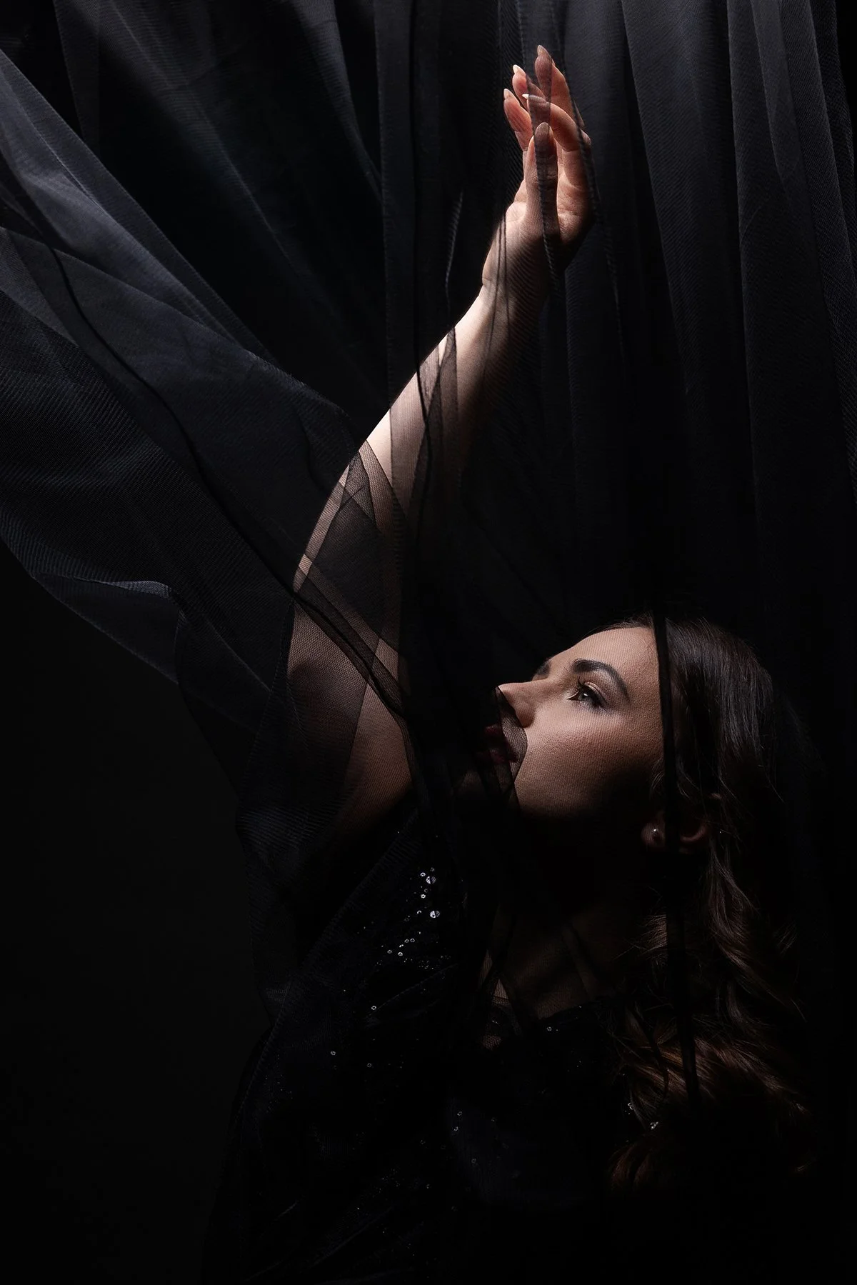 A closeup photo of a model posing with black tulle for an editorial studio photoshoot