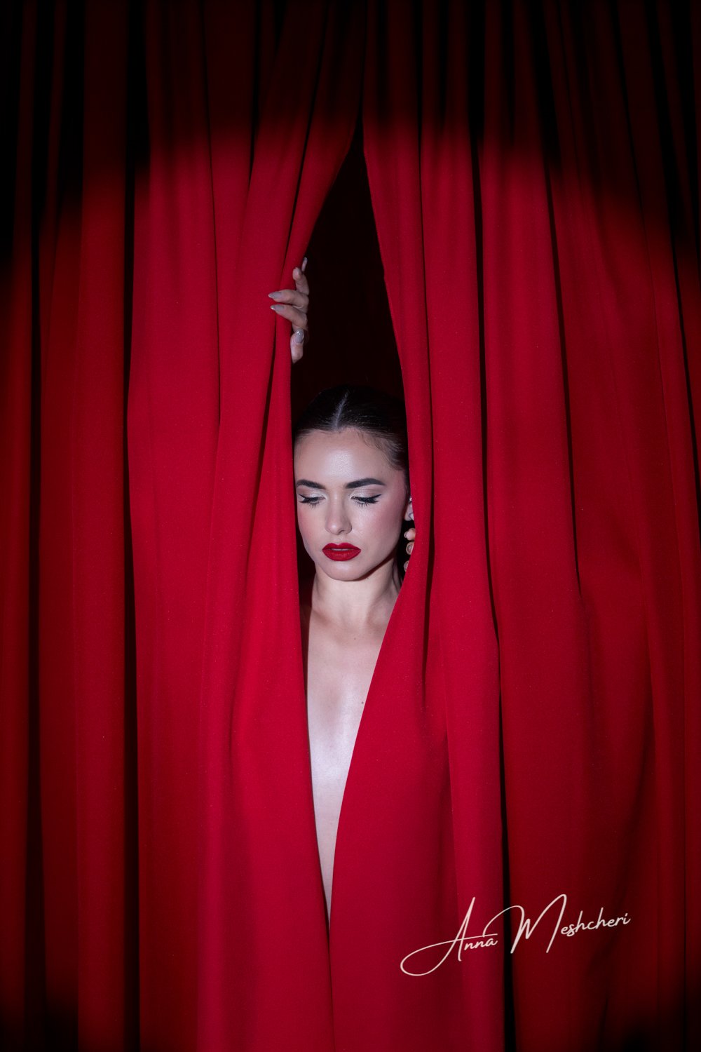 Art-inspired studio portrait featuring a model draped in flowing red fabric against a custom red backdrop with Hollywood glam styling and dramatic editorial lighting.