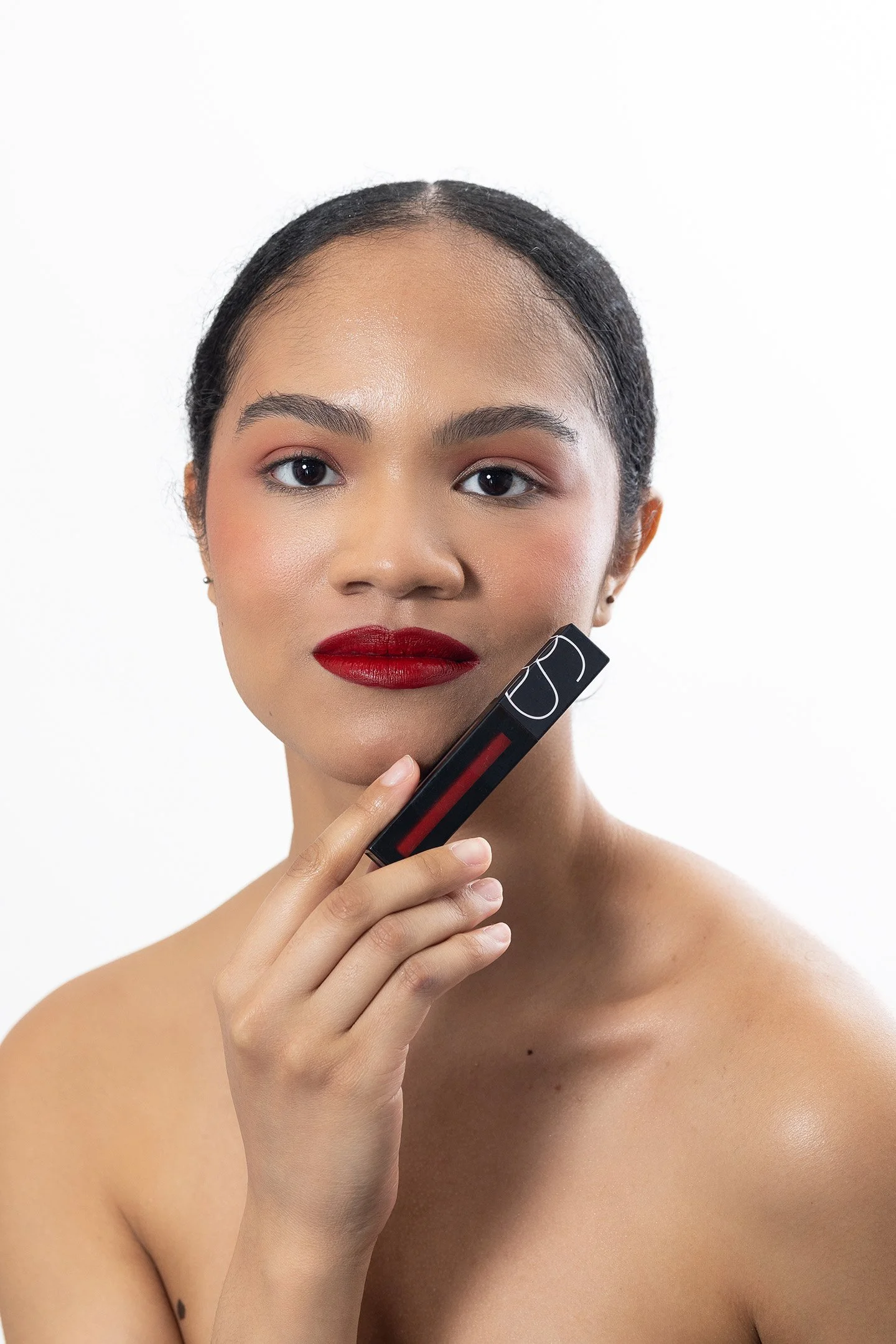 A bold studio photoshoot in New York City highlighting a beauty brand’s signature red lipstick. Featuring a clean, modern look with striking pops of color, the model’s confident expression and flawless finish capture the timeless allure of red lips.