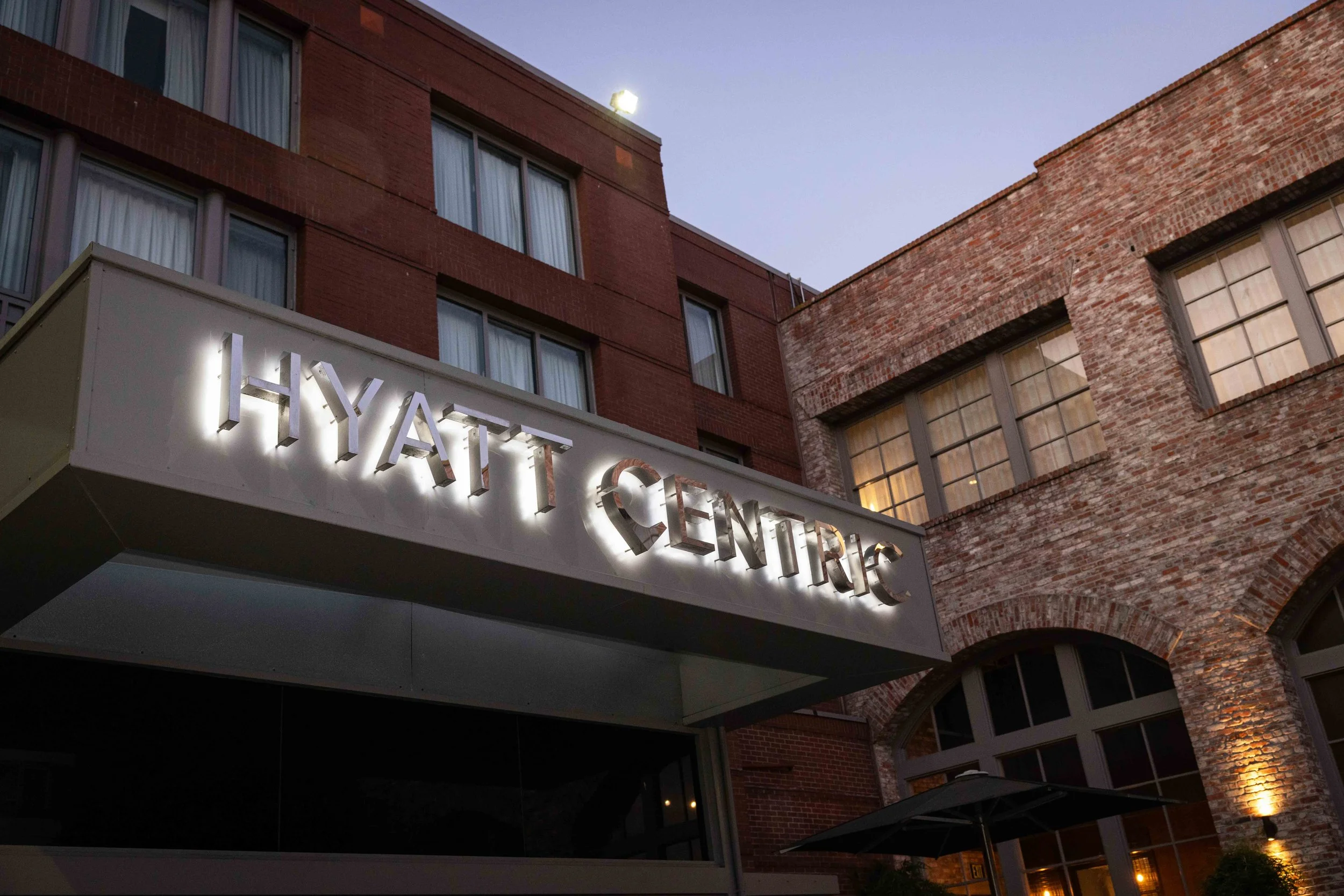 Nighttime view of a building with a sign that says 'HYATTE CENTER' illuminated, showing brick and modern architecture.