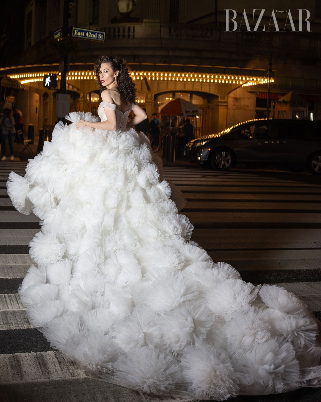 Woman in elaborate white gown walking on a city street at night. Catalogue Photography, fashion Editorial. Photographed by Anna Meshcheri
