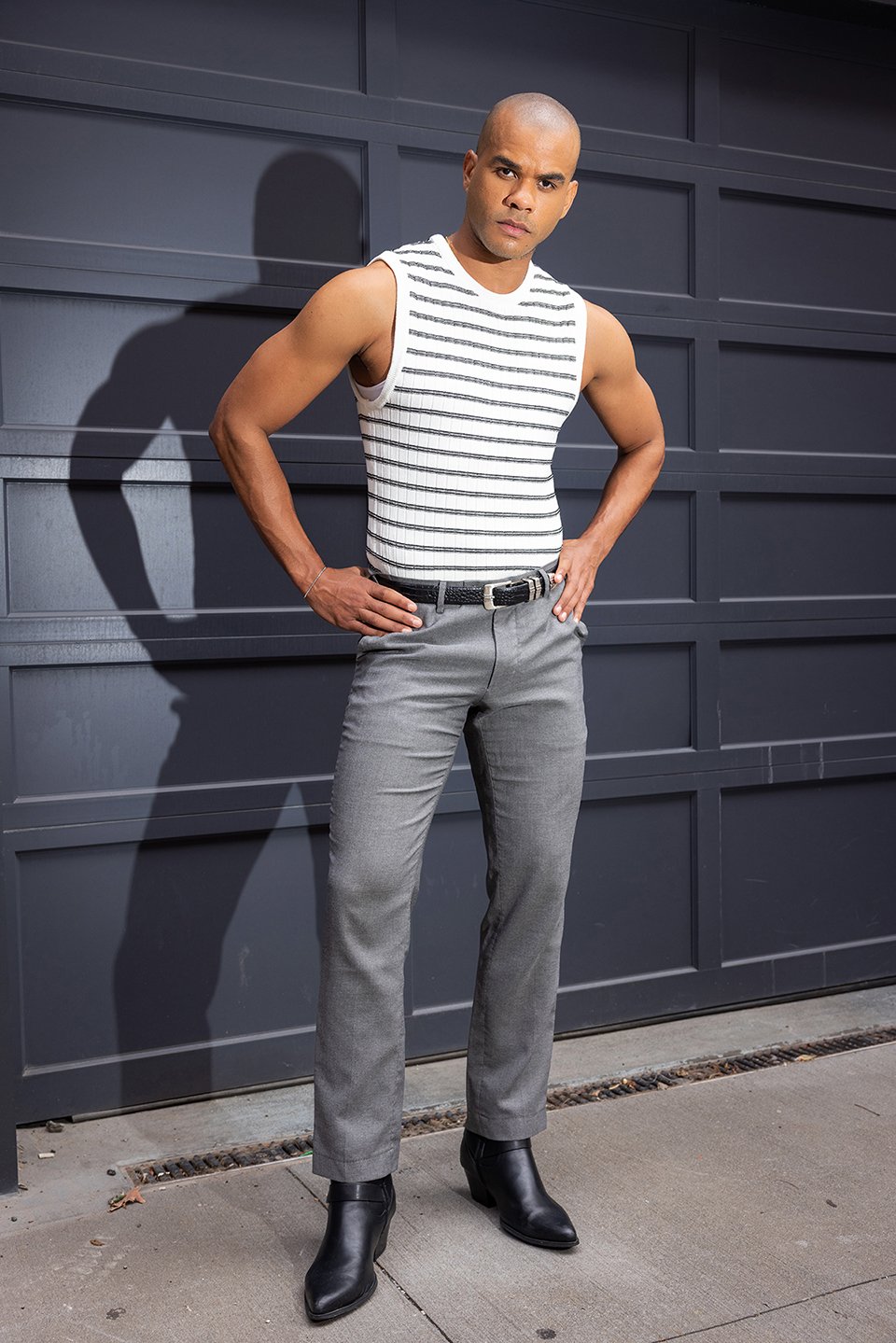 A male model posing in front os a gray garage door