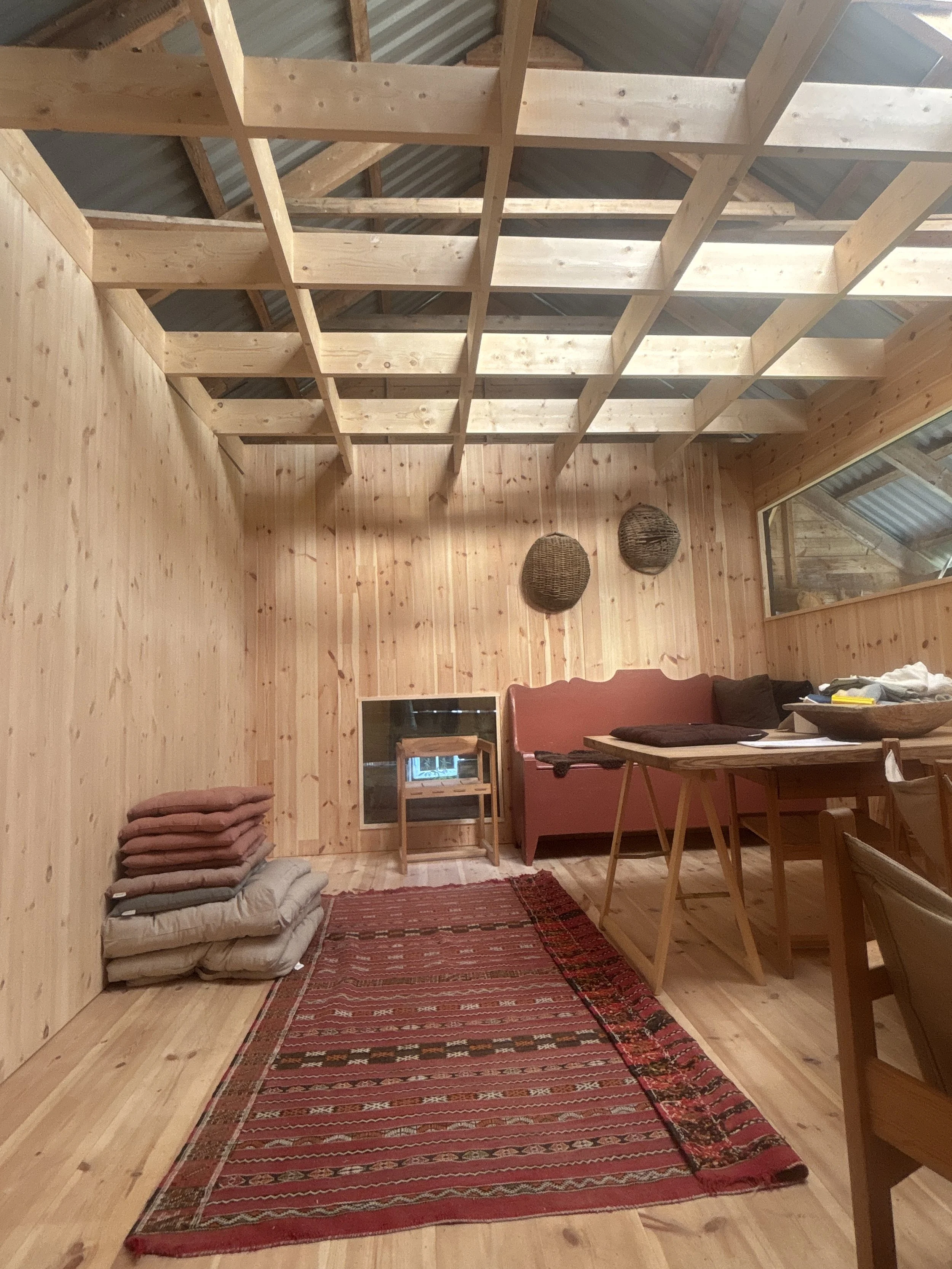 Inne i kuben er det gitt utsyn via gløttene i tømmeret på den gamle luftige låven som ble laget for høytørk