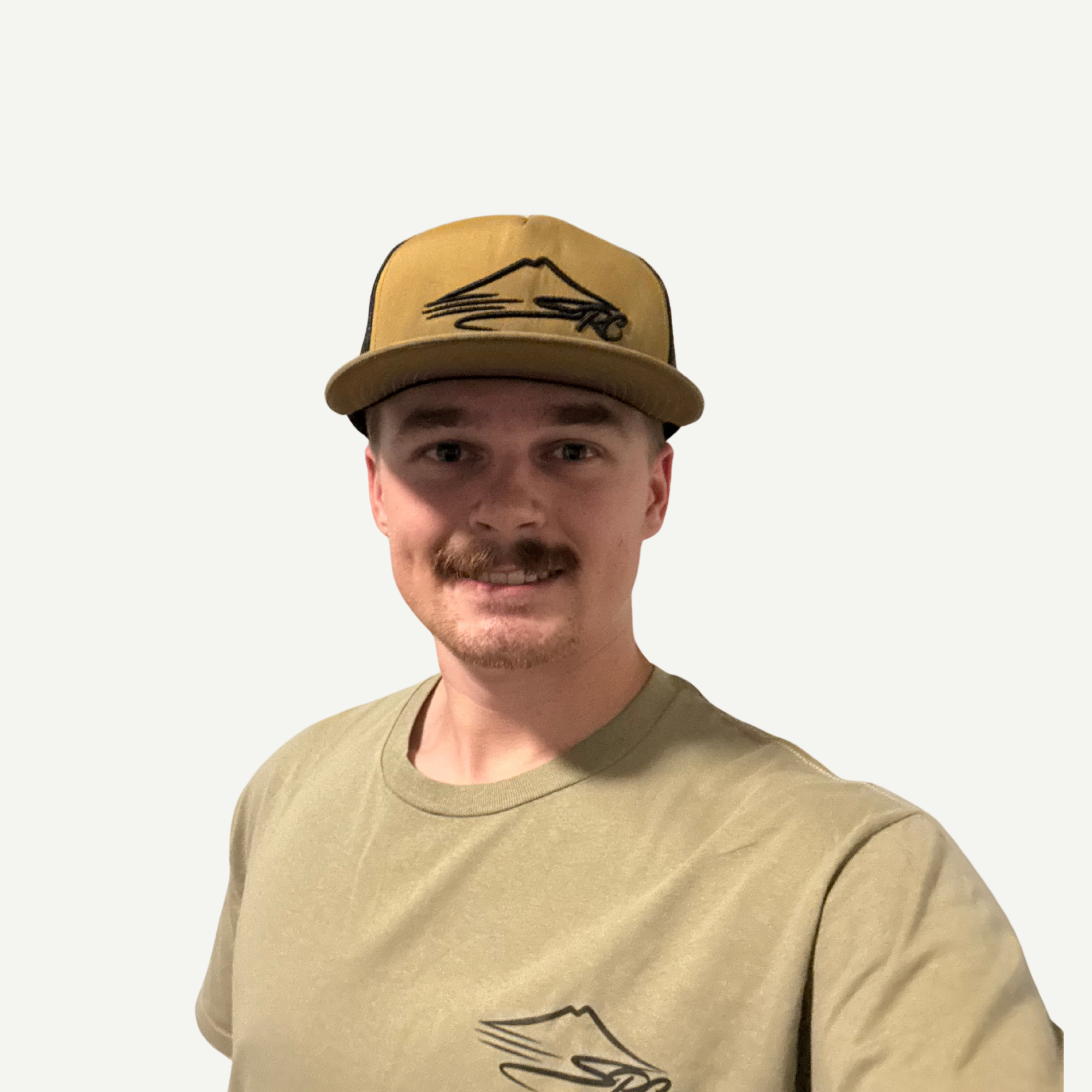 Young man wearing a beige cap with a black embroidered logo, smiling, in front of a plain light background.