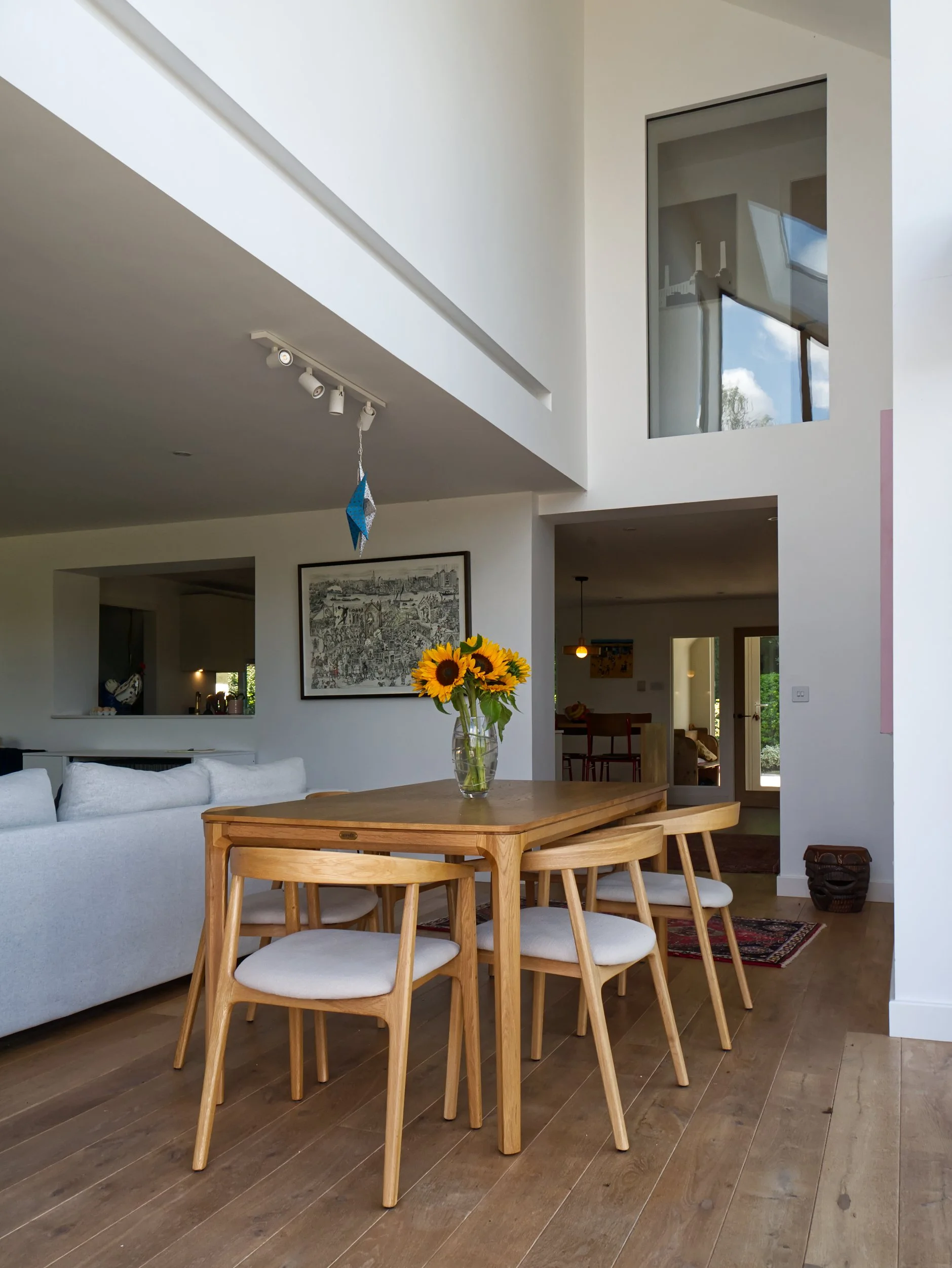 Double height dining room with mid century table and frameless glass above