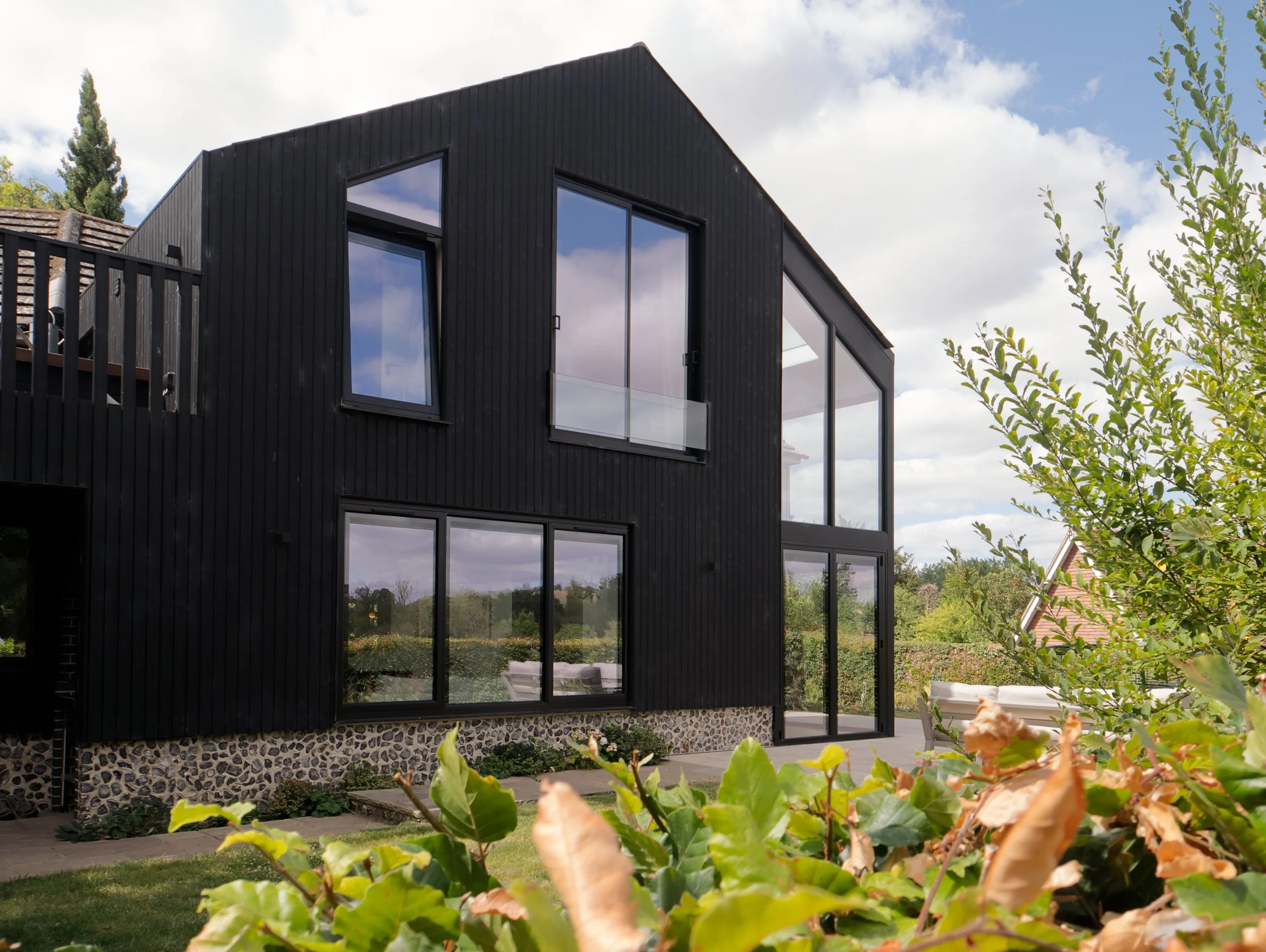 Black timber extension with flint, garden and balcony