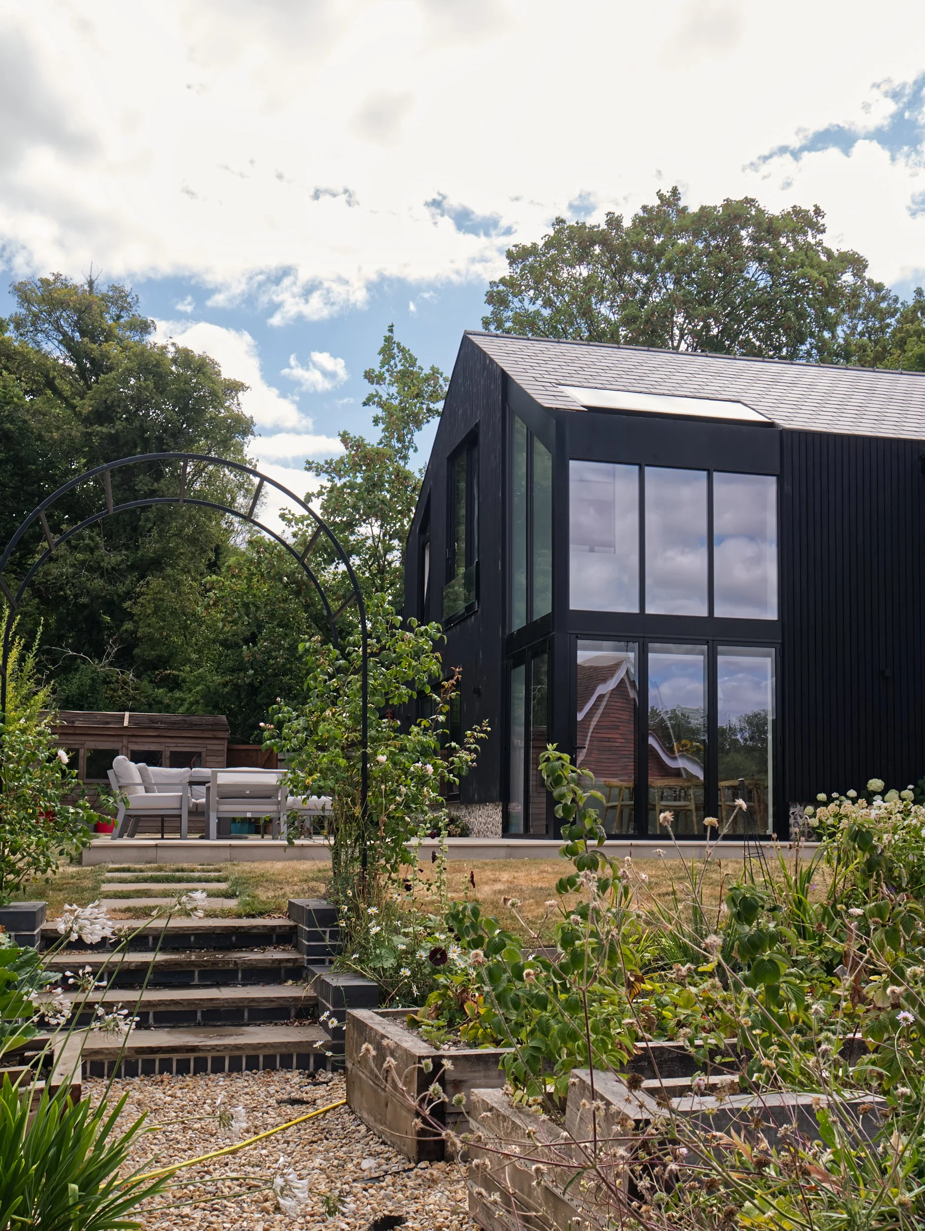 Black timber extension with flint, garden and balcony