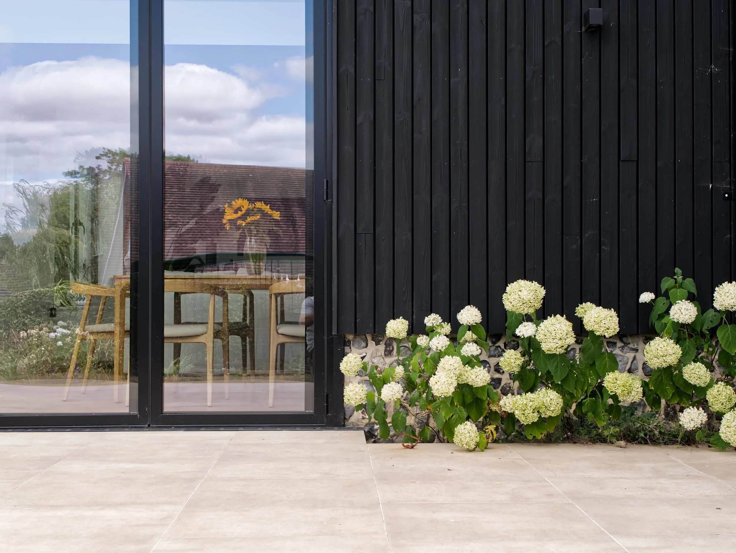 Black timber extension with flint, garden and balcony