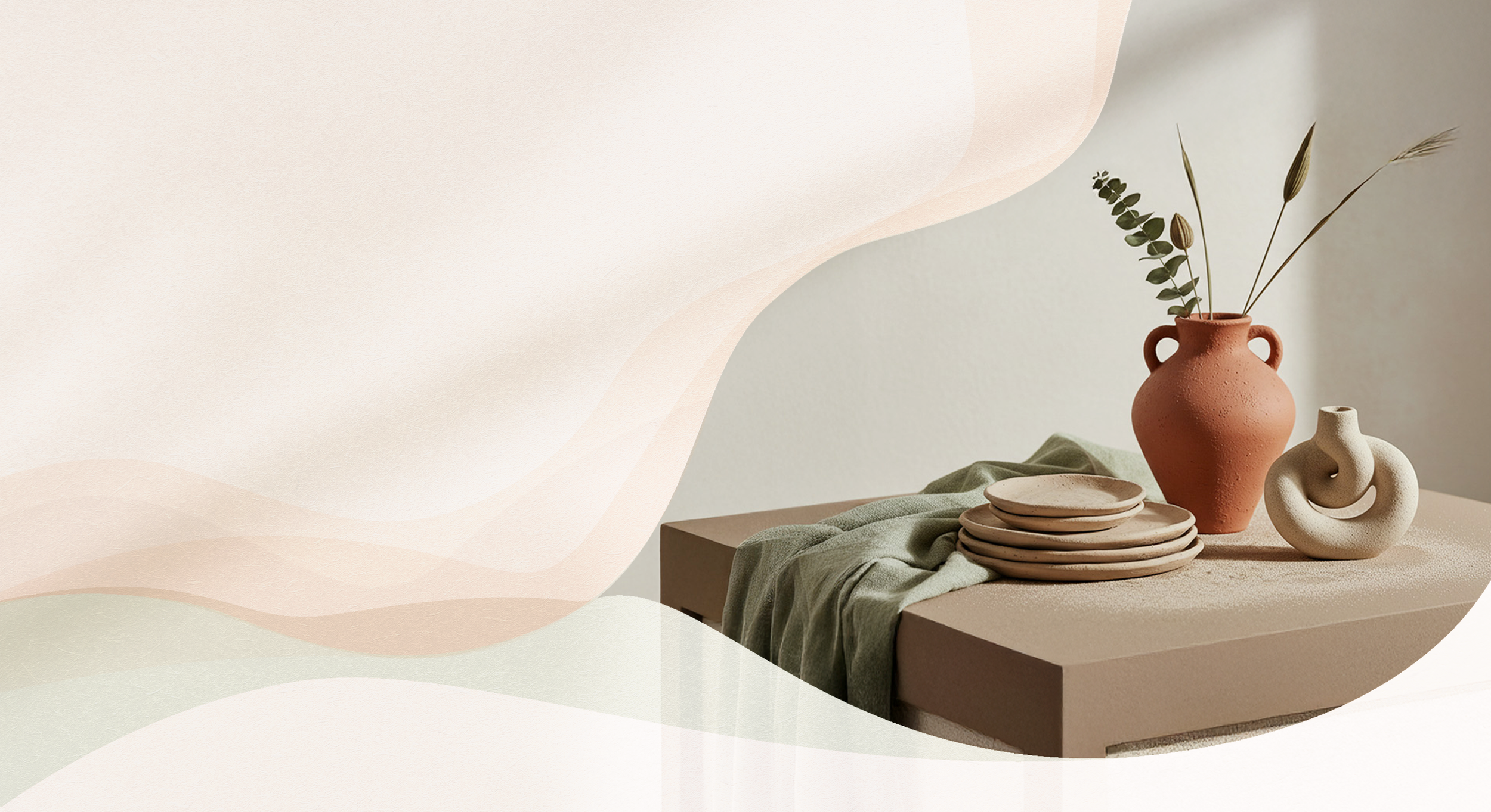 A beige table set with a green cloth, stacked beige plates, a terracotta vase with dried foliage, and a textured cream-colored sculpture, against a light-colored wall.