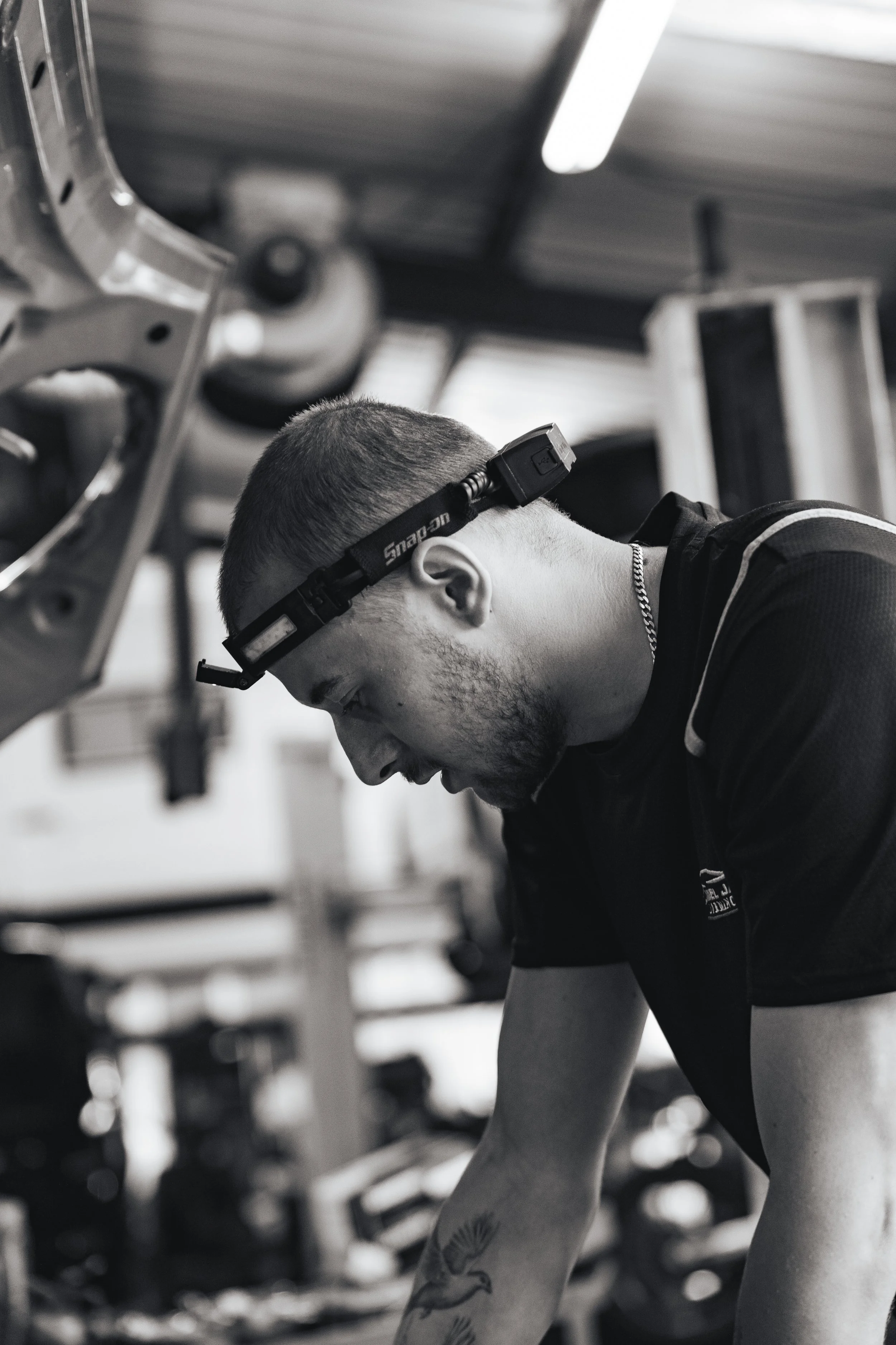 A man wearing a headlamp is working on a mechanical project in a workshop.