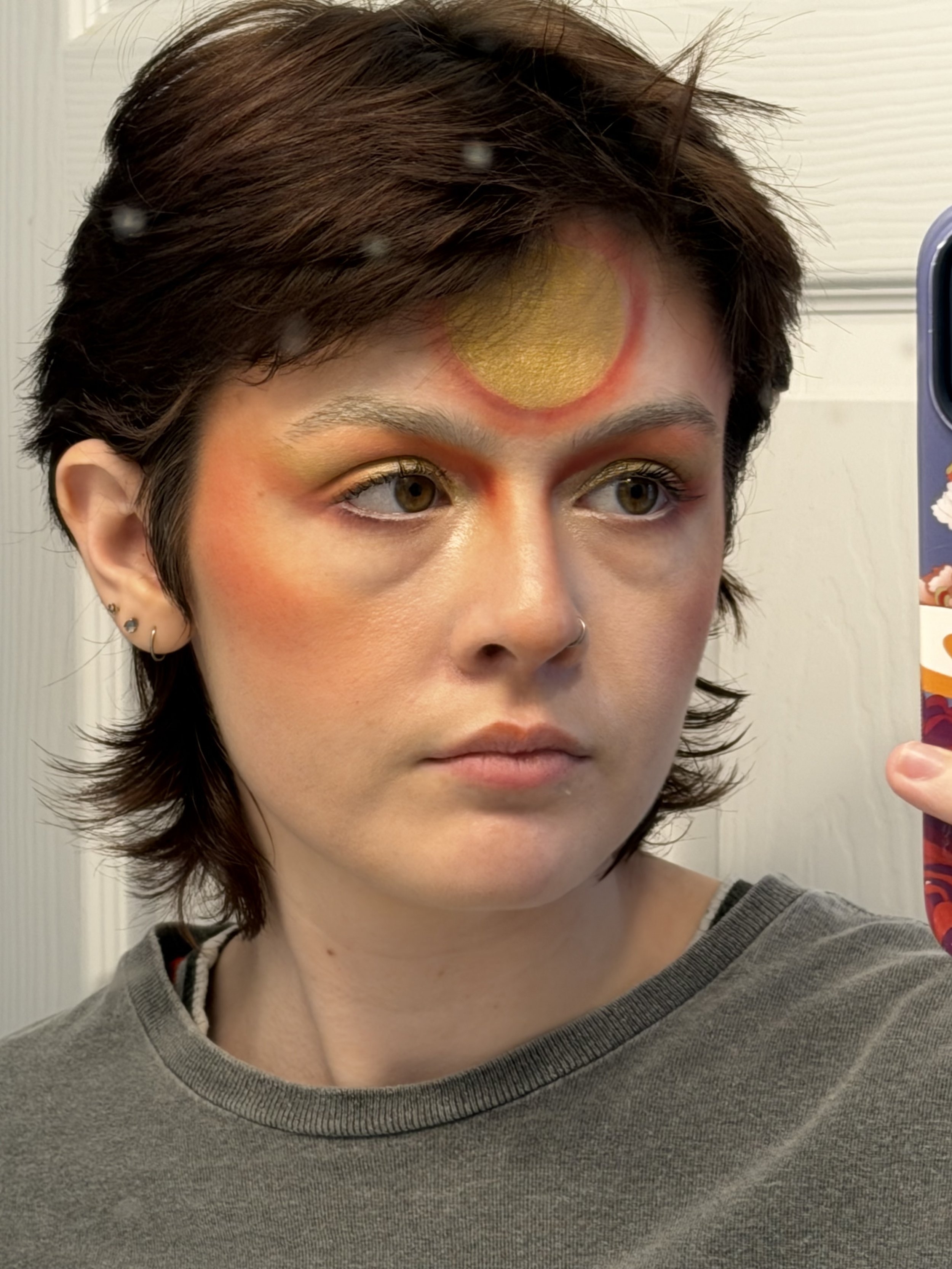 Two people dressed in costumes stand in front of a stone wall at night. The woman on the left wears a black dress with a veil, a red flower crown, and red Converse shoes. The man on the right wears a black suit with a red tie and black shoes.