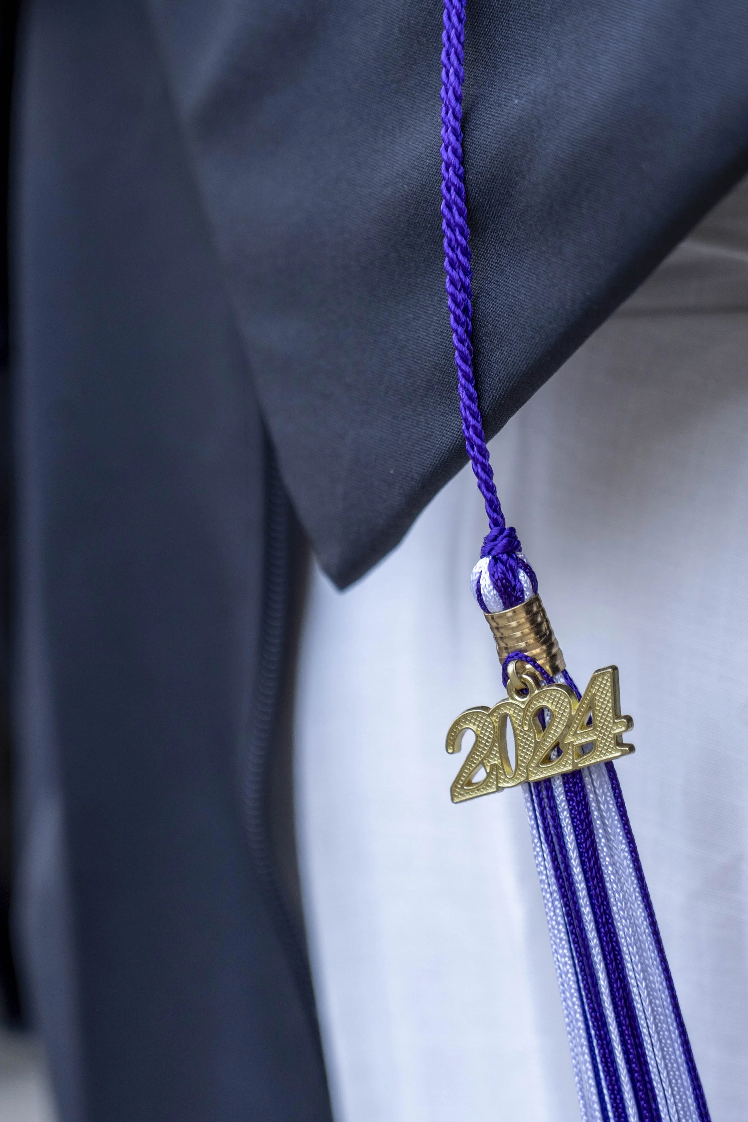 A graduation cap with a purple and white tassel and a gold '2024' charm.