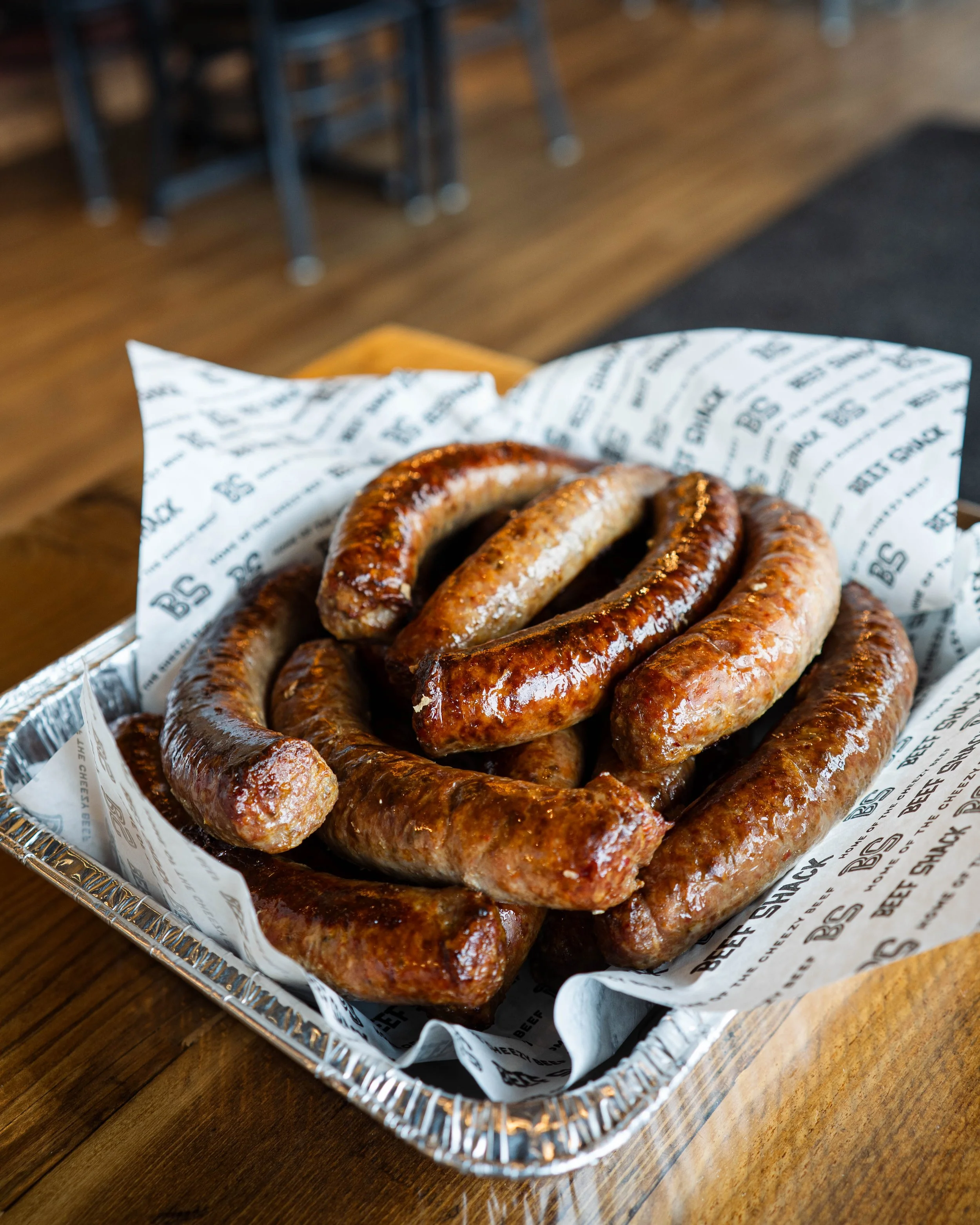 A tray of cooked sausages on parchment paper on a wooden table.
