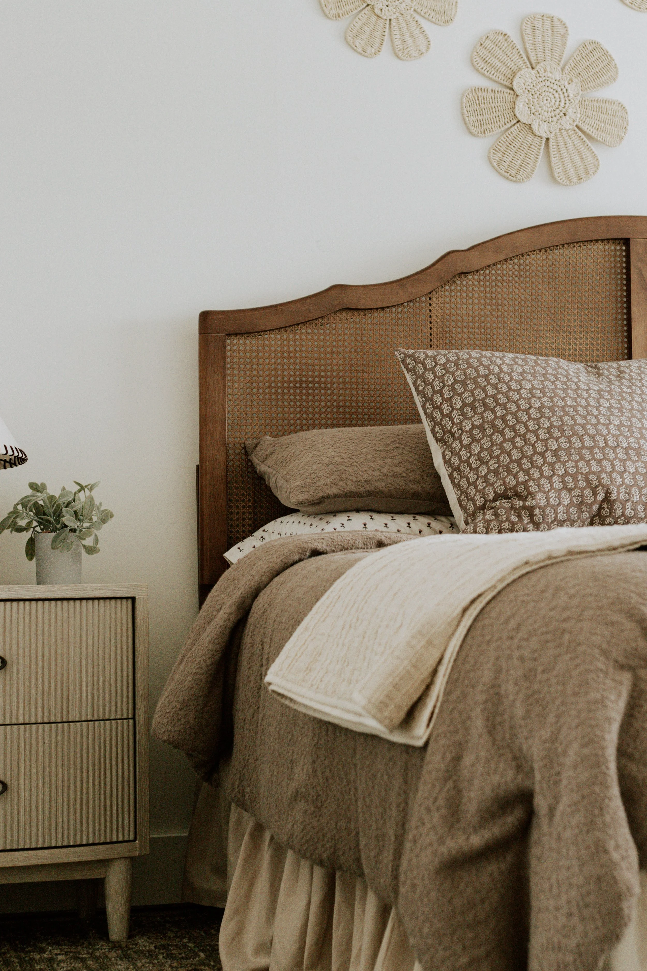 Vintage-inspired bedroom with warm wood furniture, patterned textiles and layered neutral furnishings.