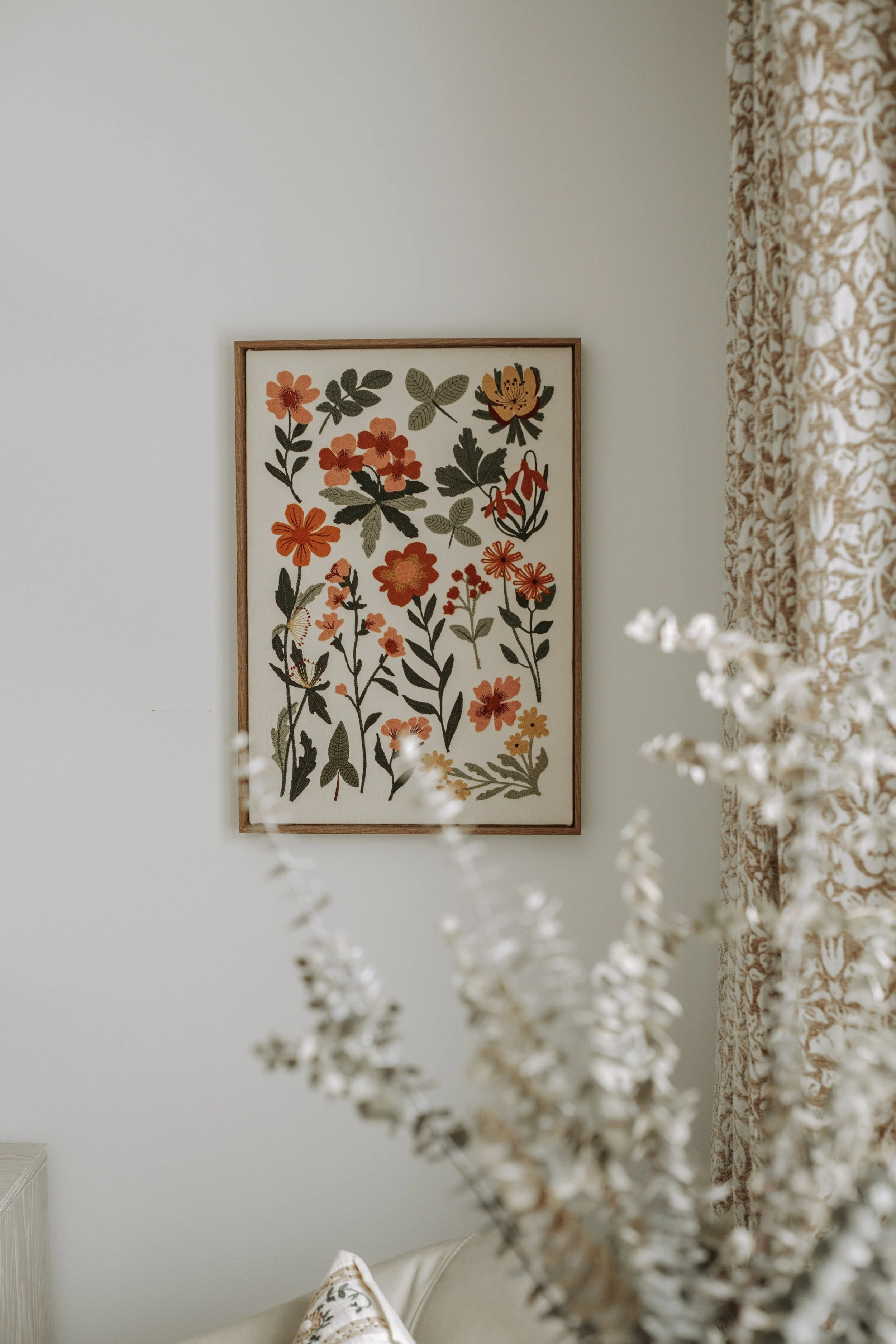 Vintage floral artwork paired with patterned window treatments in a layered bedroom interior.