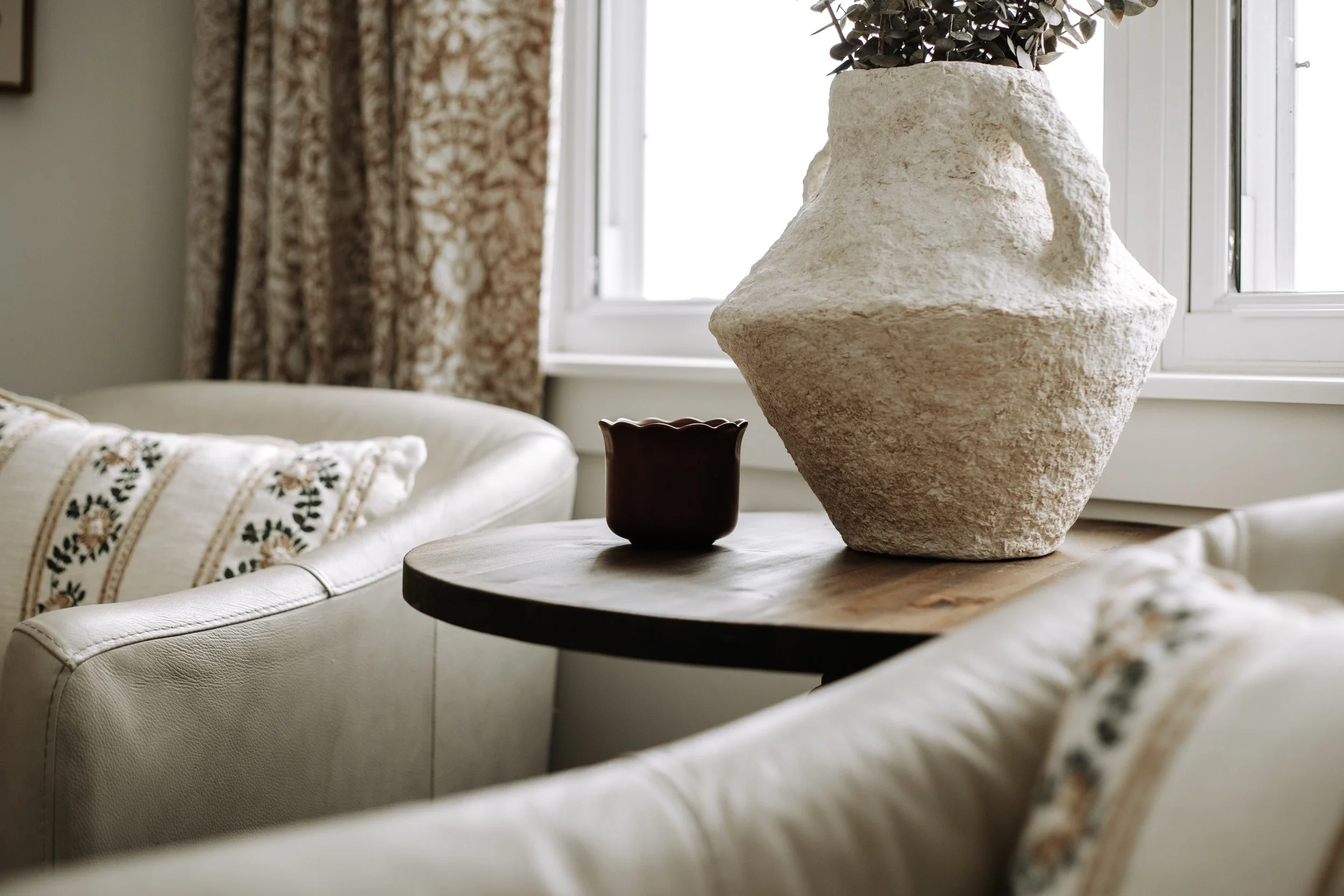 Layered bedroom interior featuring warm neutrals, patterned textiles and vintage-inspired furnishings.