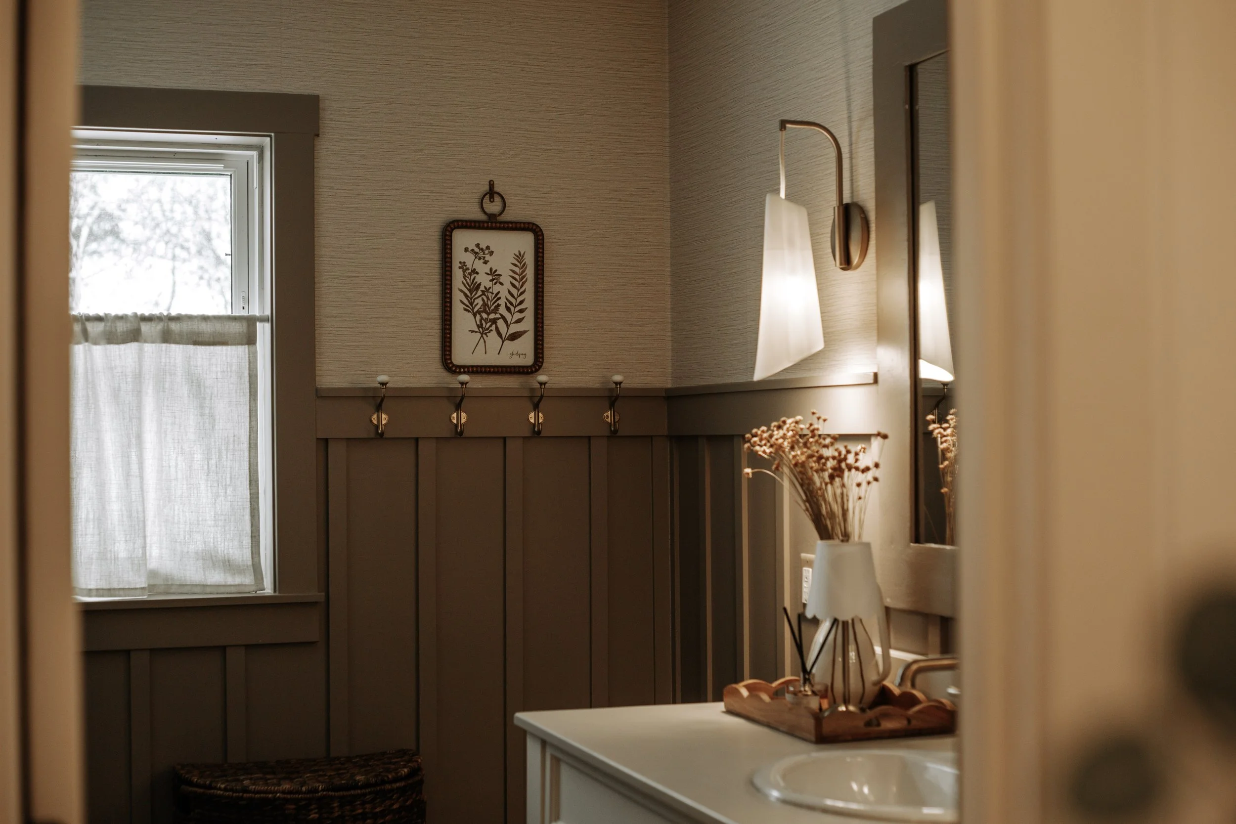 Vintage-inspired bathroom refresh with wainscoting, warm brass details and thoughtfully layered finishes.