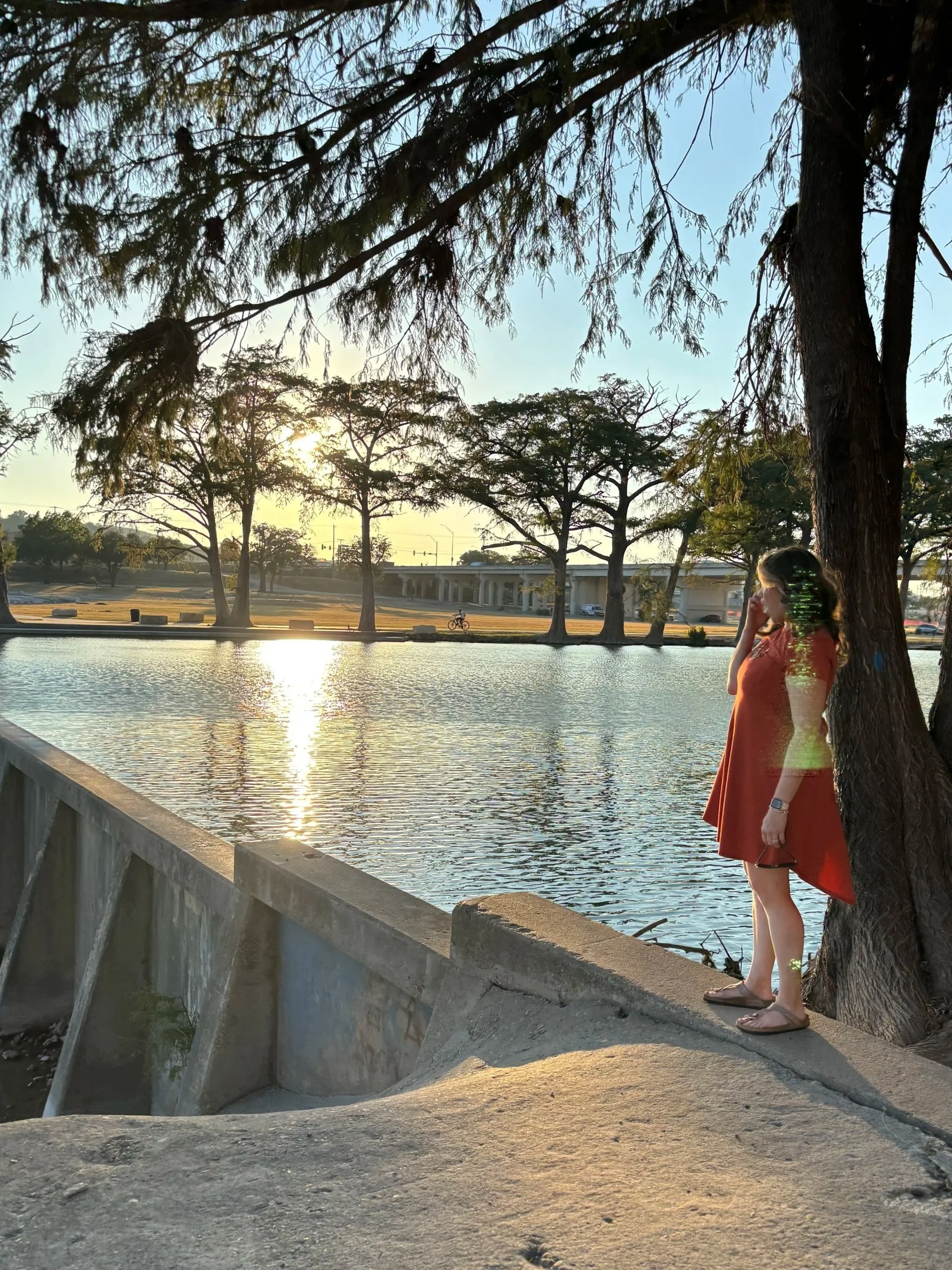 Elaine standing by a river at sunset