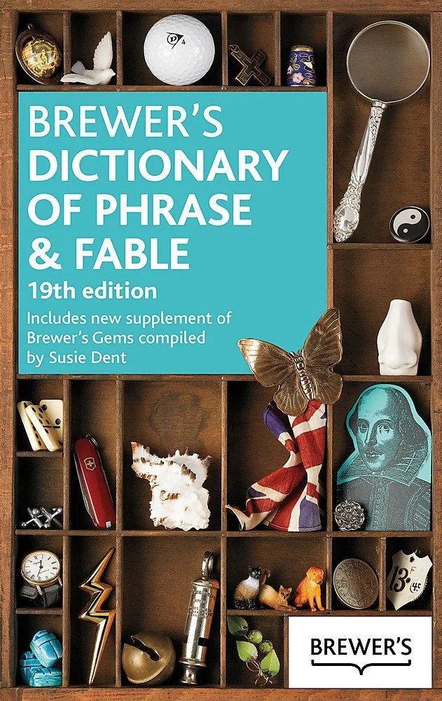 Cover of Brewer's Dictionary of Phrase & Fable, 19th edition, featuring a wooden compartment with various small objects, including a golf ball, a butterfly, a Union Jack sock, a portrait in line art, and other items. A new section by Susie Dent.