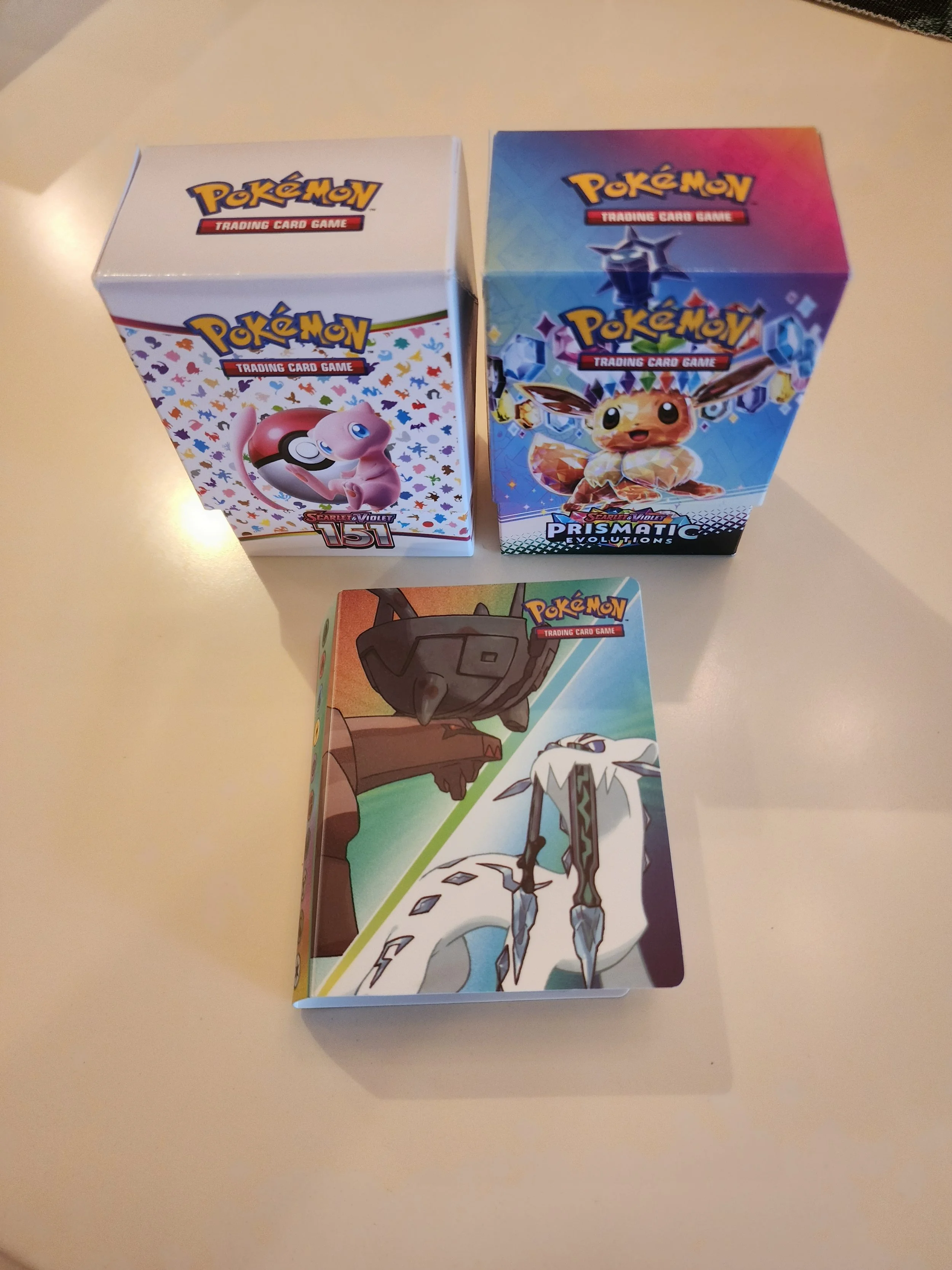 Three Pokémon trading card game booster boxes on a white surface, featuring different Pokémon characters on their packaging.