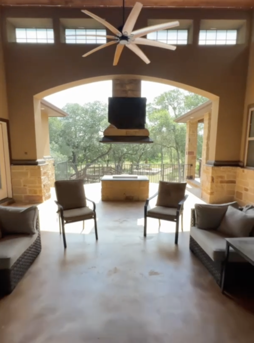 Indoor living room with pool table overlooking a lush outdoor area, featuring stone accents, ceiling fan, and seating.