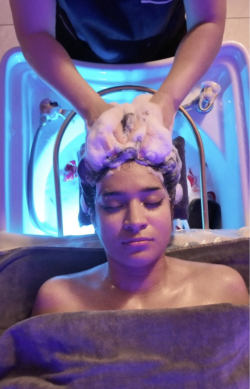 Person receiving a head massage in a spa or wellness center with blue lighting.