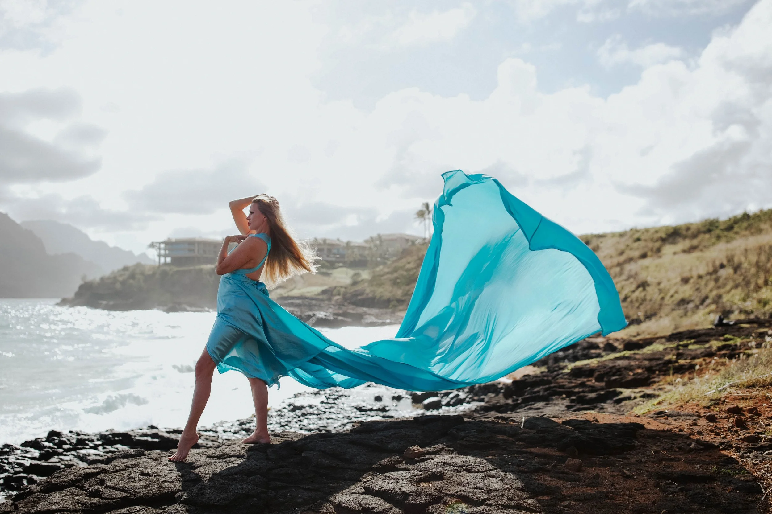 Model wearing blue flowing dress near rocks on Cozumel beach