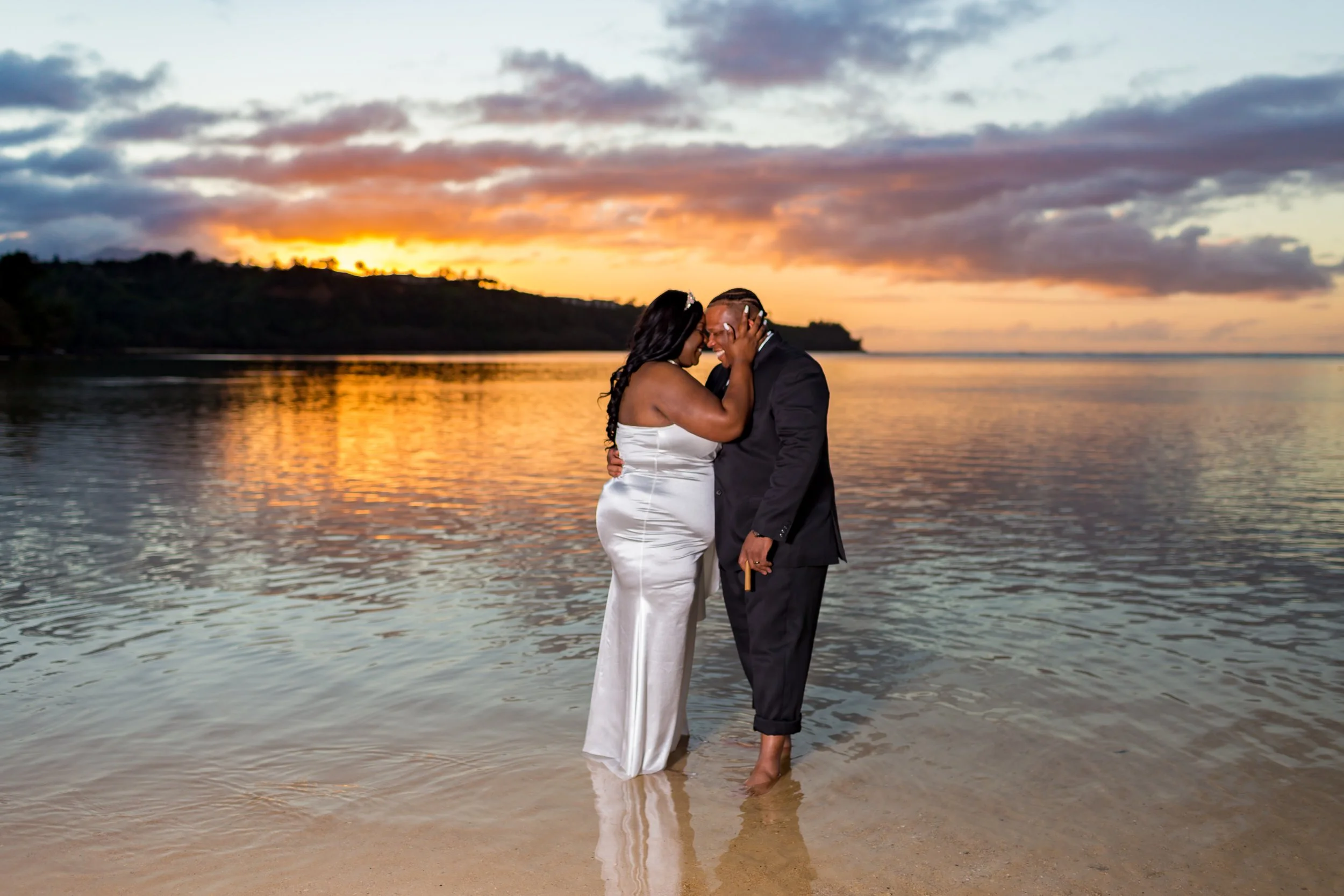 Wedding couple standing in shallow water on beach at sunset in Cozumel
