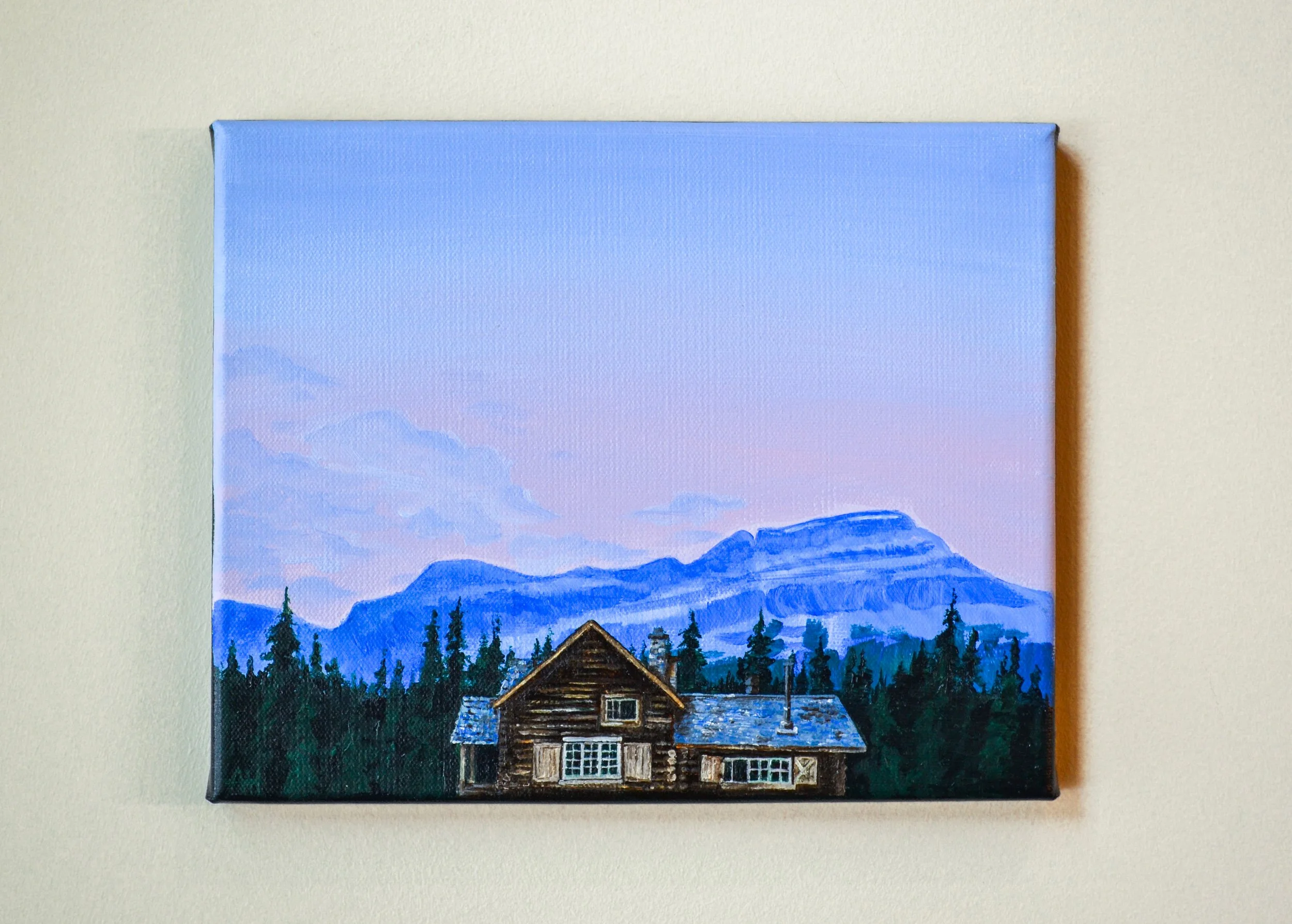 Rustic cabin painting against mountains